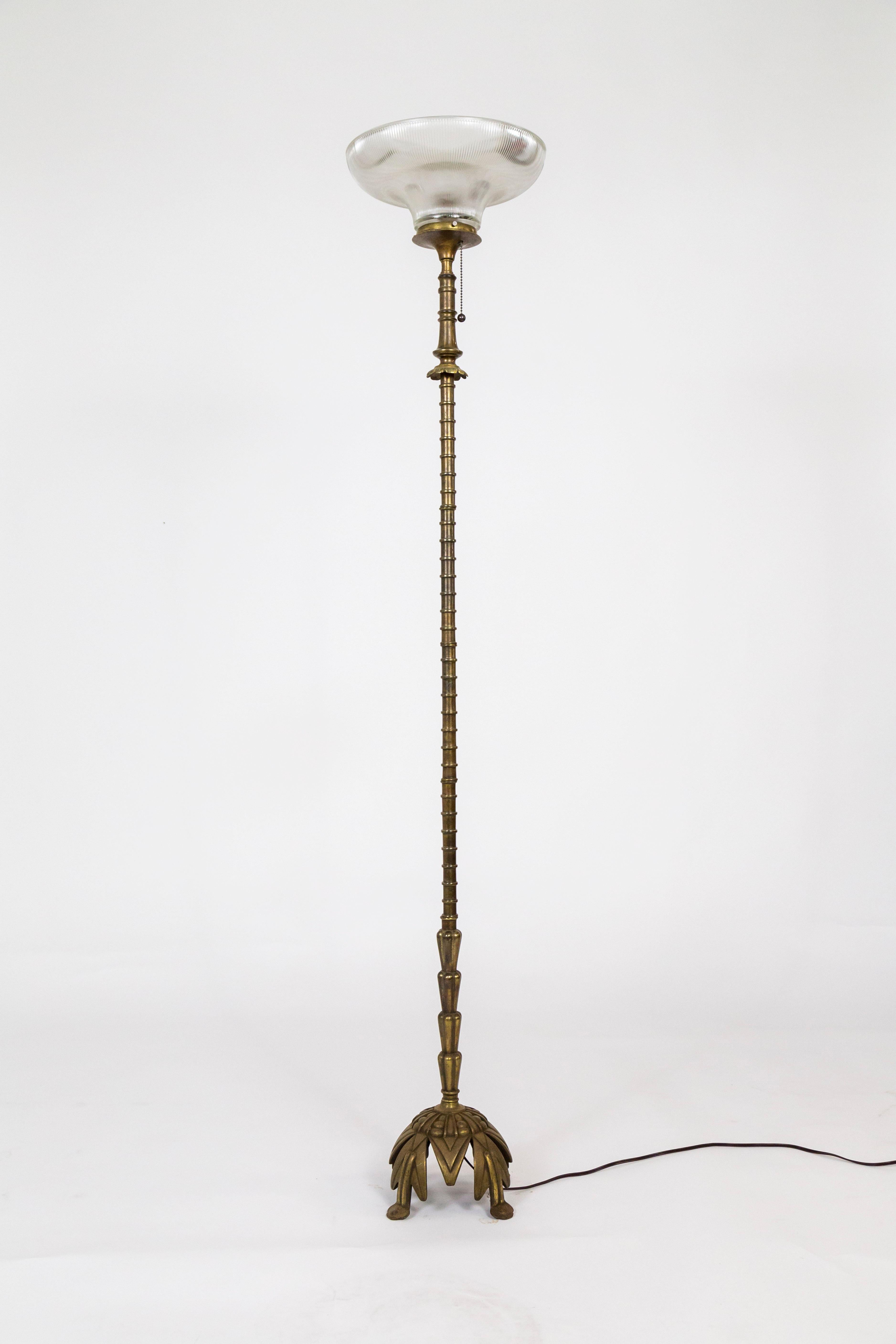 A bronze floor lamp with well crafted Deco designs: a very cool elevated base, ribbed stem, and flower accent by the pull chain; an uplight with a Holophane glass shade. By Rembrandt Lamp Company, signed inside of base: “PAT APP FOR Rembrandt 7079.”