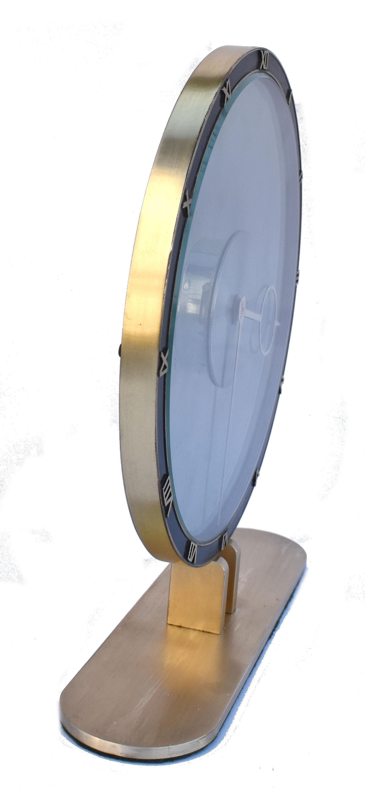 Superbly stylish is this wonderful Art Deco 8 day clock by Kienzel. Beautiful bluey grey colored glass and brass desk timepiece is typical of the 1930s.
The bronze case is highly polished and lacquered. The chapter ring with raised brass Roman
