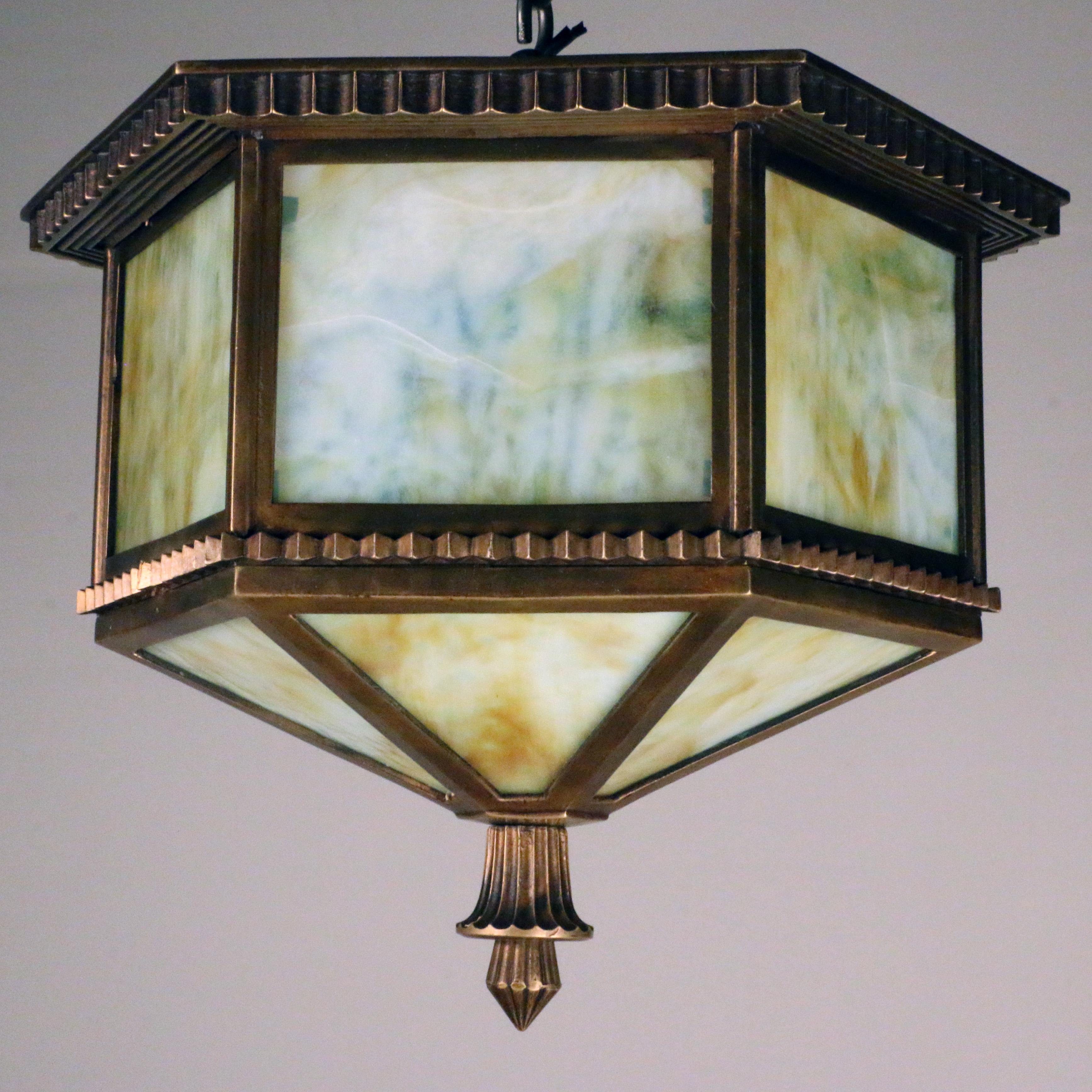 This well-cast bronze fixture has a wonderful patina that is enhanced by the art glass green slag panels.
From the paneled sides and base it emits a soft glow when lit. It is of substantial weight and quality..built to last.
This lantern is on the
