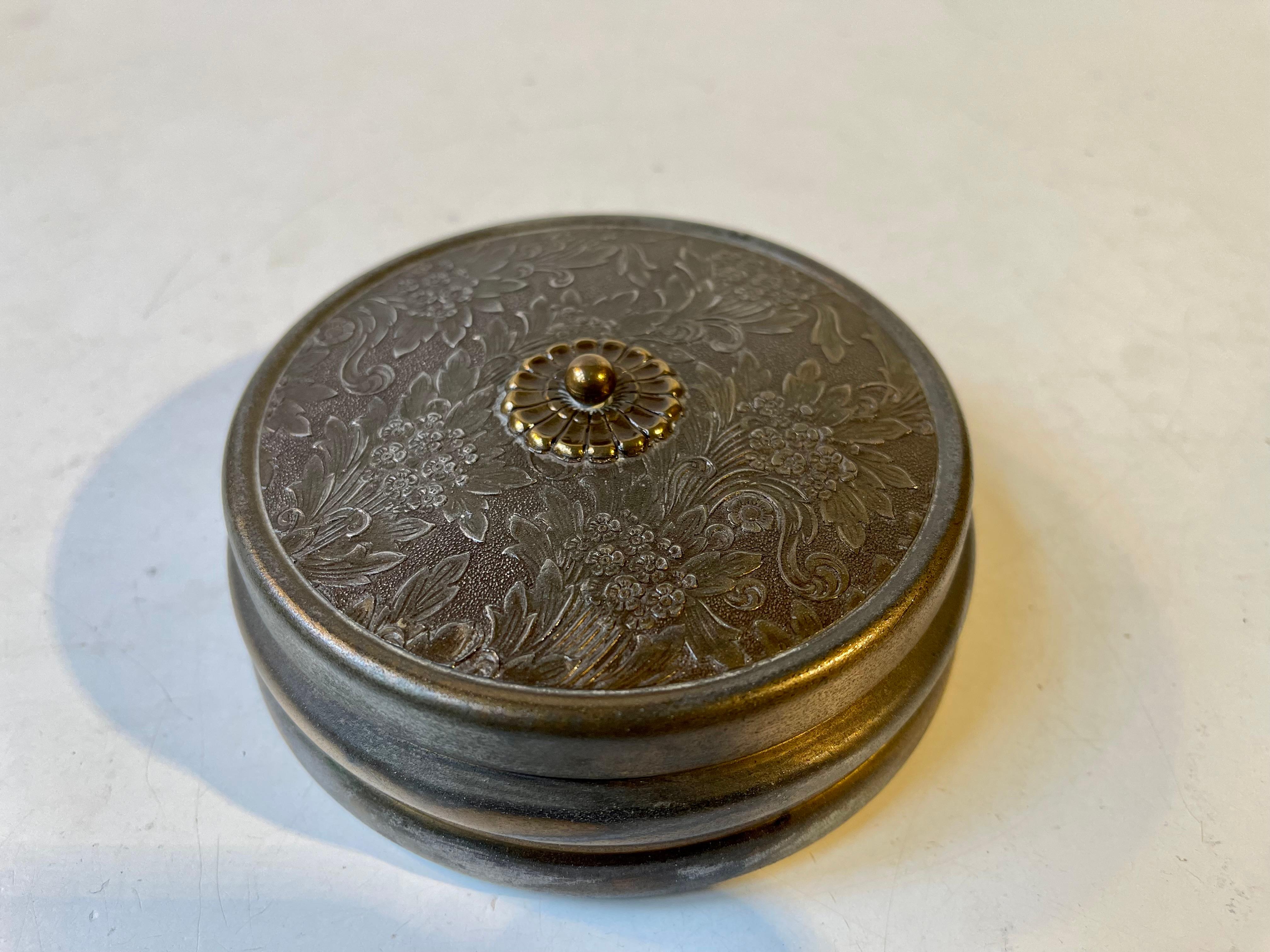 Japanese inspired jewelry trinket in bronze. The lid is hand- decorated/cut in relief depicting bouquets of flowers. It has a red velvet interior and a mirror to the underside of the flipping lid. This piece is marked Bronze and was made by an