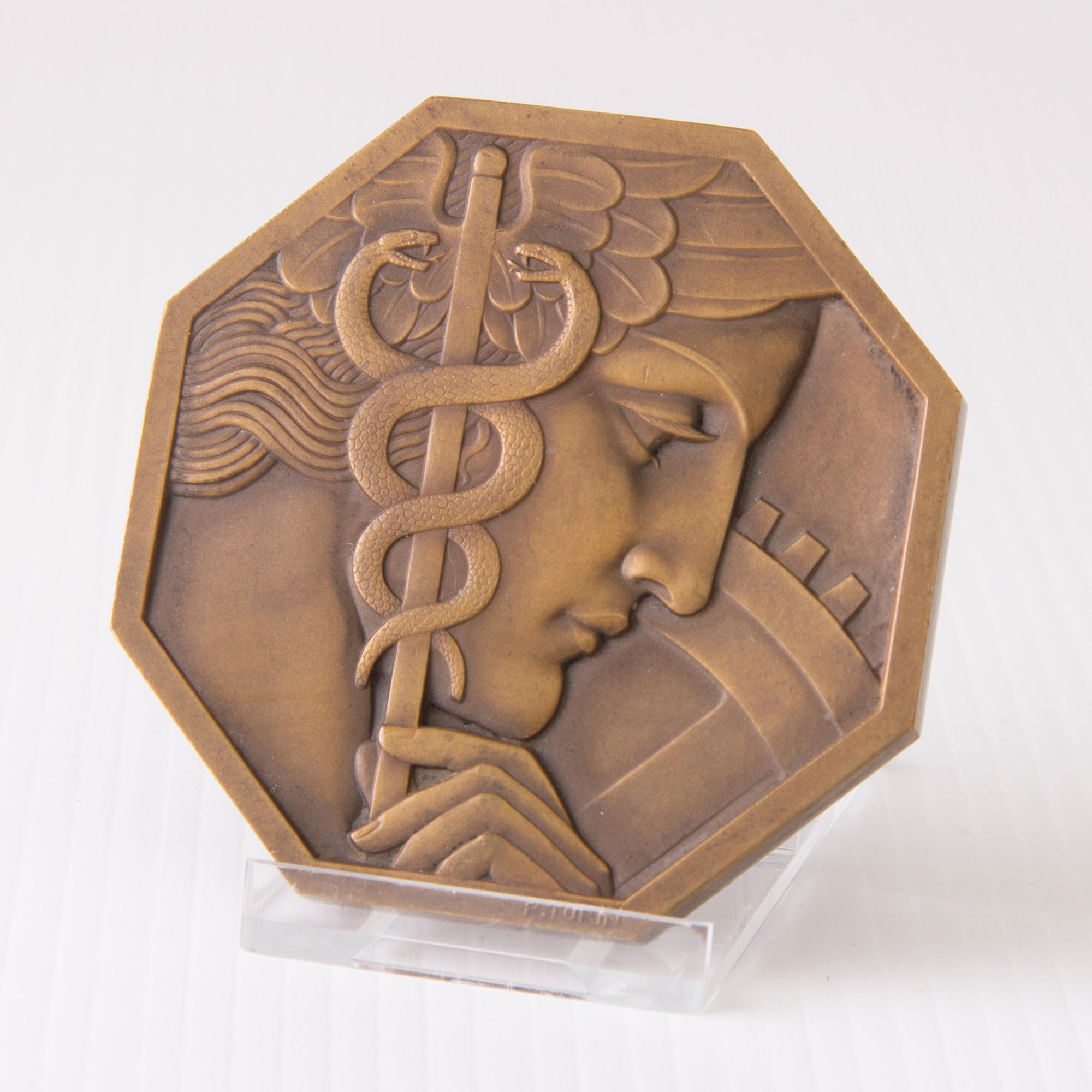 Art Deco bronze medal comite français des expositions,
Designed by Pierre Turin.
Measures: H 7 cm, W 7 cm, D 1 cm
French, circa 1930
In this powerful octagonal medal and Art Deco design Turin’s imagery combines the god Mercury, perhaps as an