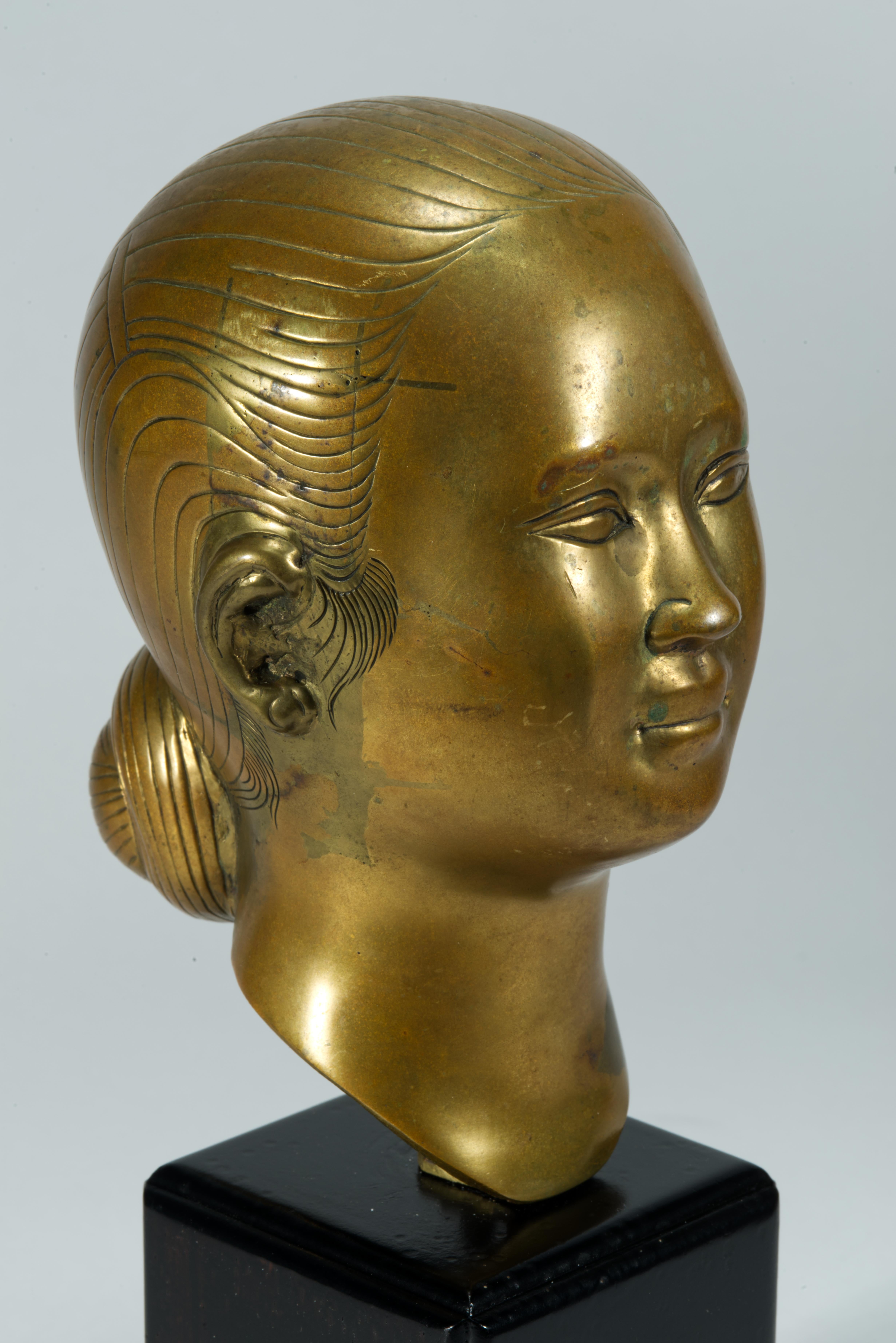 Il busto o scultura vintage presenta una testa femminile in bronzo non laccato, montata a vite su un basamento in legno patinato nero o ebanizzato. La scultura non è contrassegnata e manca degli adesivi di carta, ma può essere attribuita a Nguyen Le