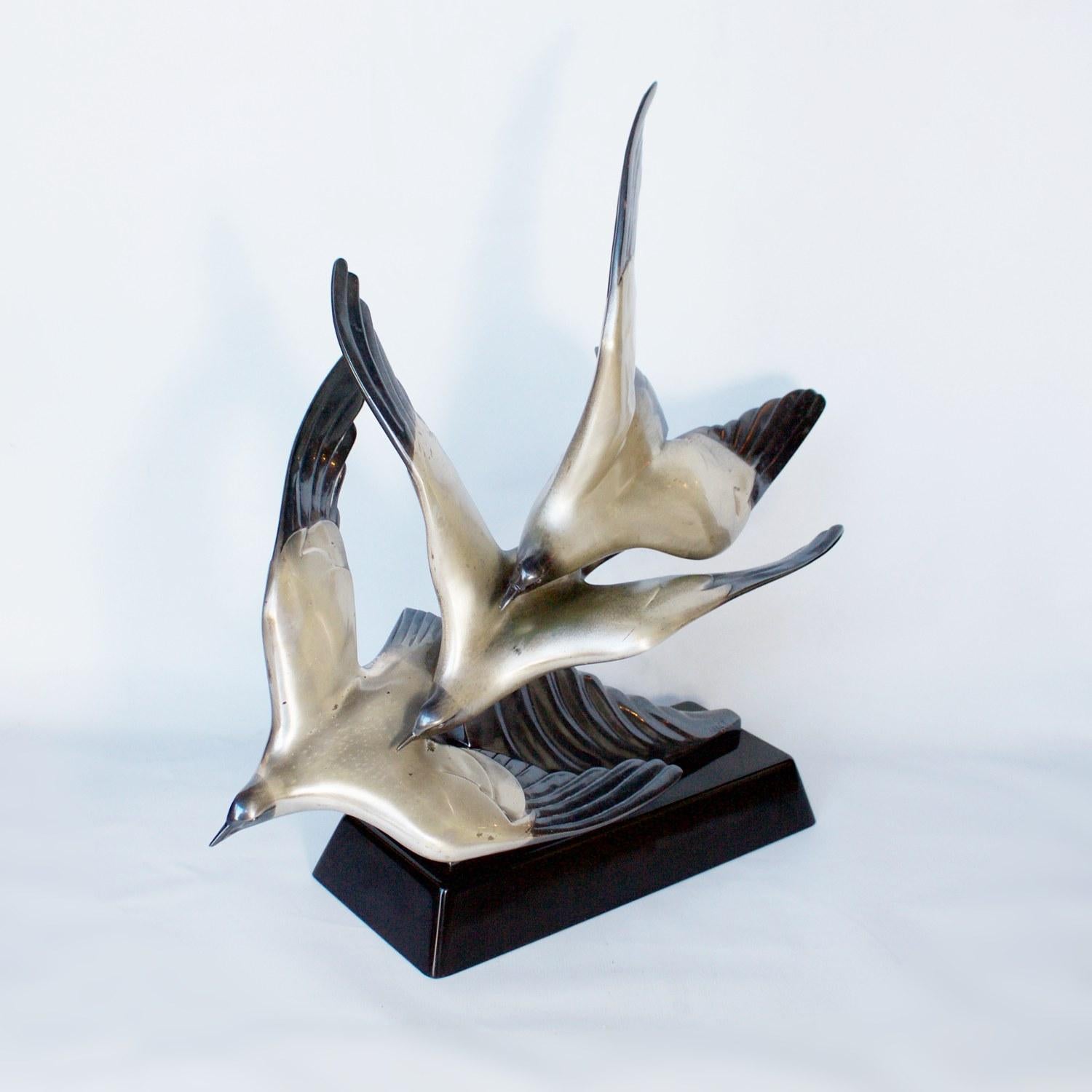 An Art Deco patinated and parcel silvered bronze sculpture depicting three flying seagulls, swooping close to the rising sea swell. Set over an angular black stone base. Signed to cast and stamped Etling Paris to back of base. 

Artist: Alexandre