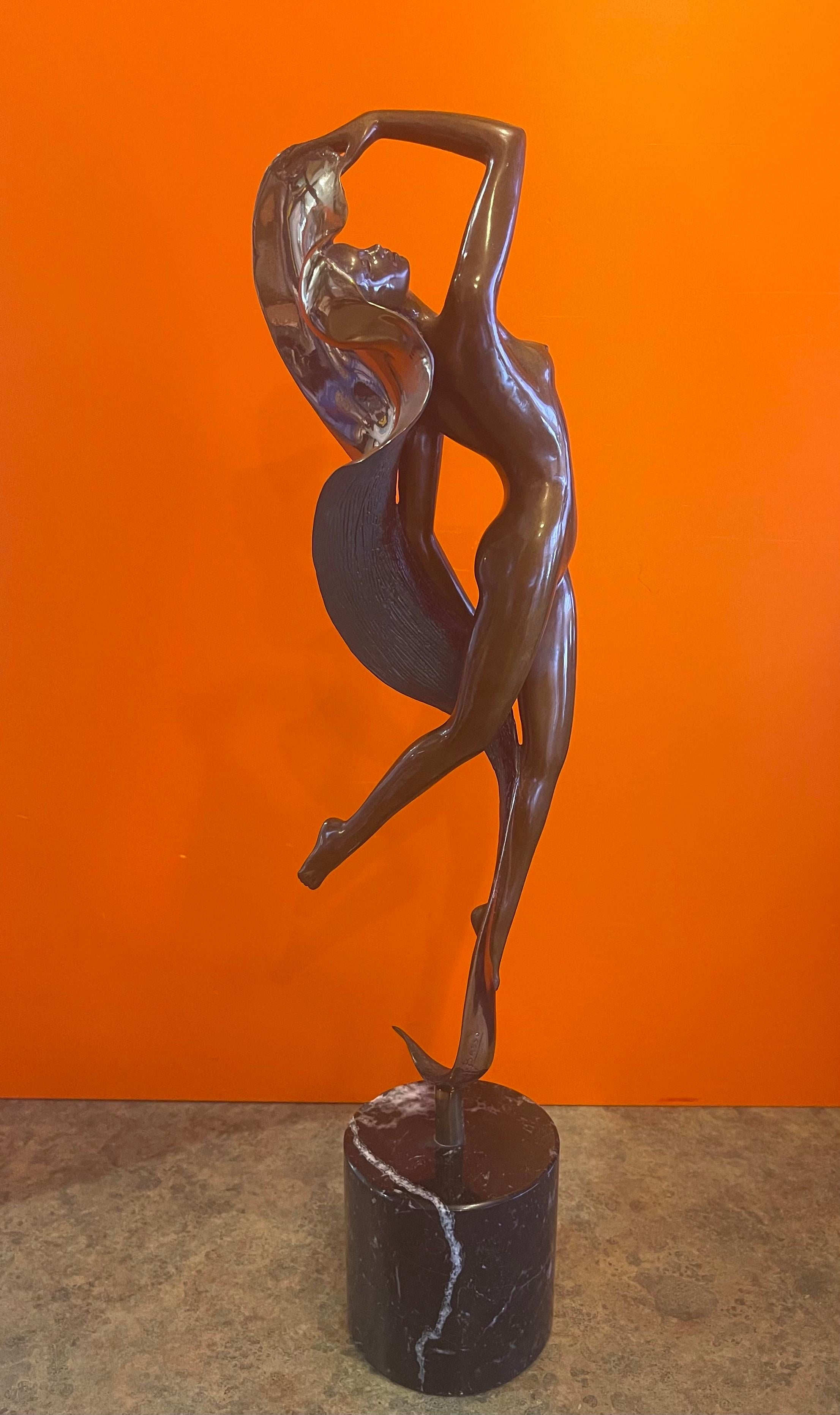 Merveilleuse sculpture Art déco en bronze sur une base en marbre noir par Angelo Basso, circa 1986. L'œuvre représente une élégante jeune femme aux seins nus dansant avec une ceinture tourbillonnante. La patine délicate est complétée par un bronze