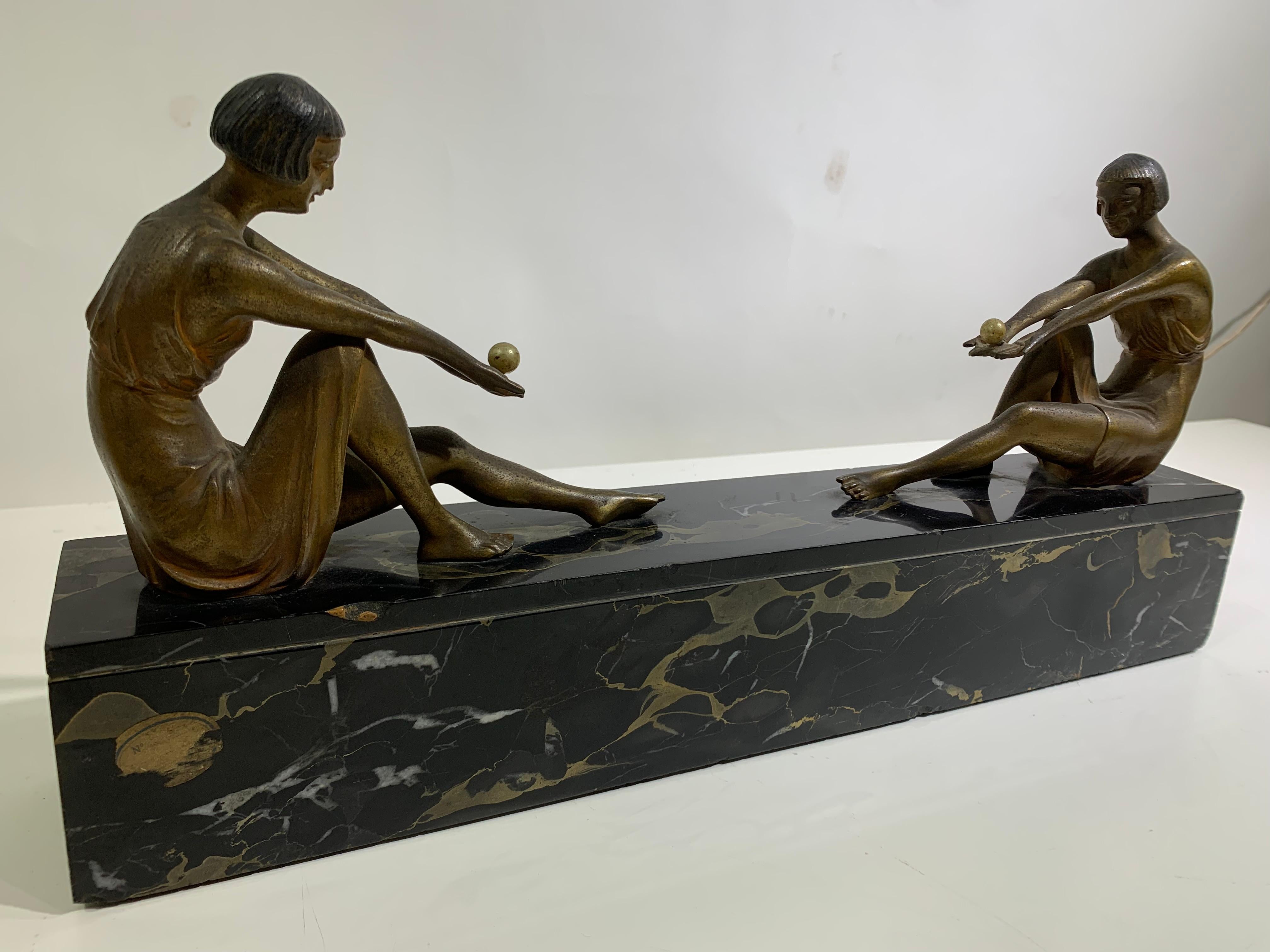 Art Deco bronze statue of two young women facing each other resting on a solid marble base. 
Dressed in the fashion of the day with curled bob hair cuts.