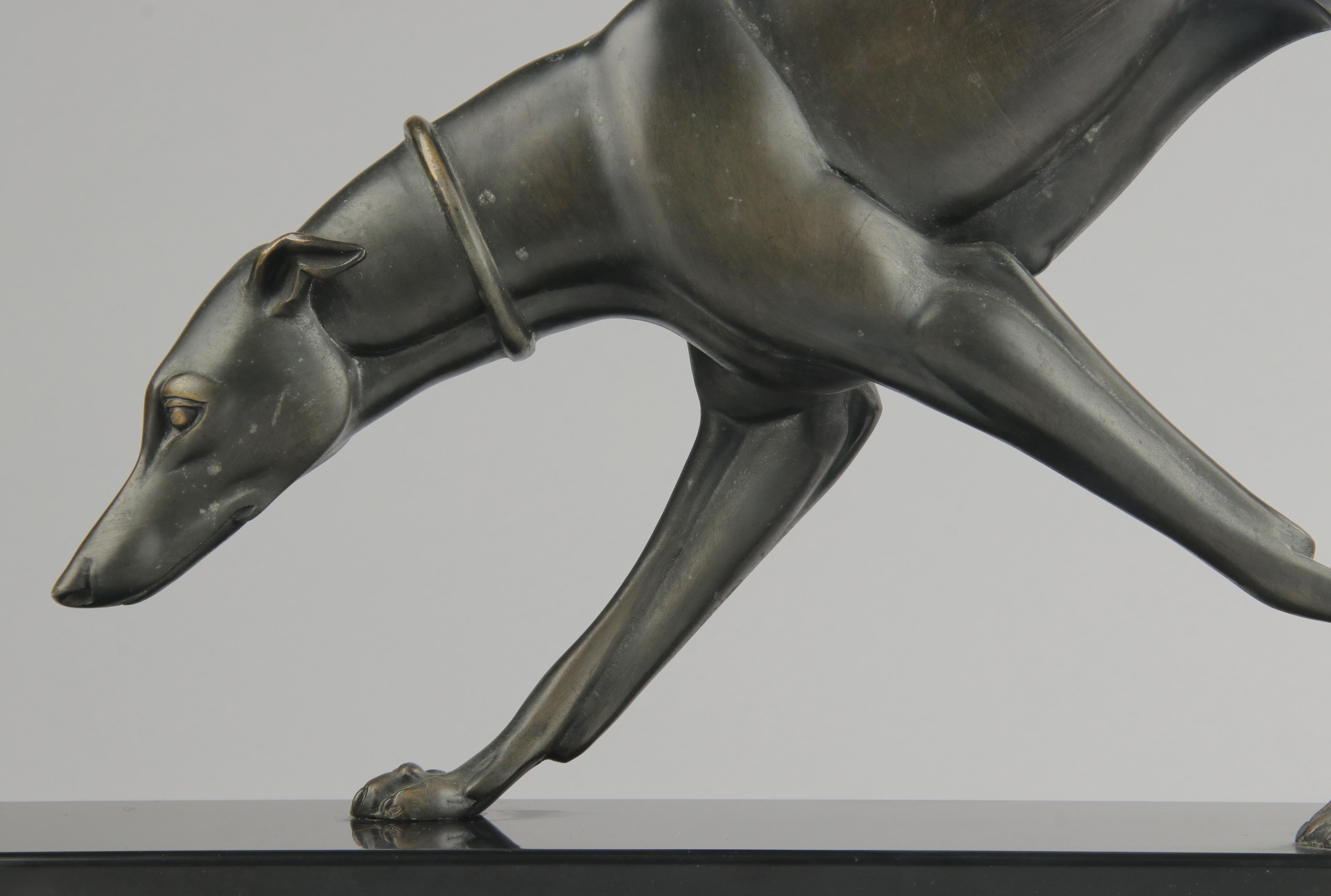 A large sculpture of a greyhound / whippet. The sculpture is made of dark green patinated bronze. On a belgian black marble plinth. The statue is signed on the plinth: Rochard. It is a thin, clear and beautiful signature. The statue is made in