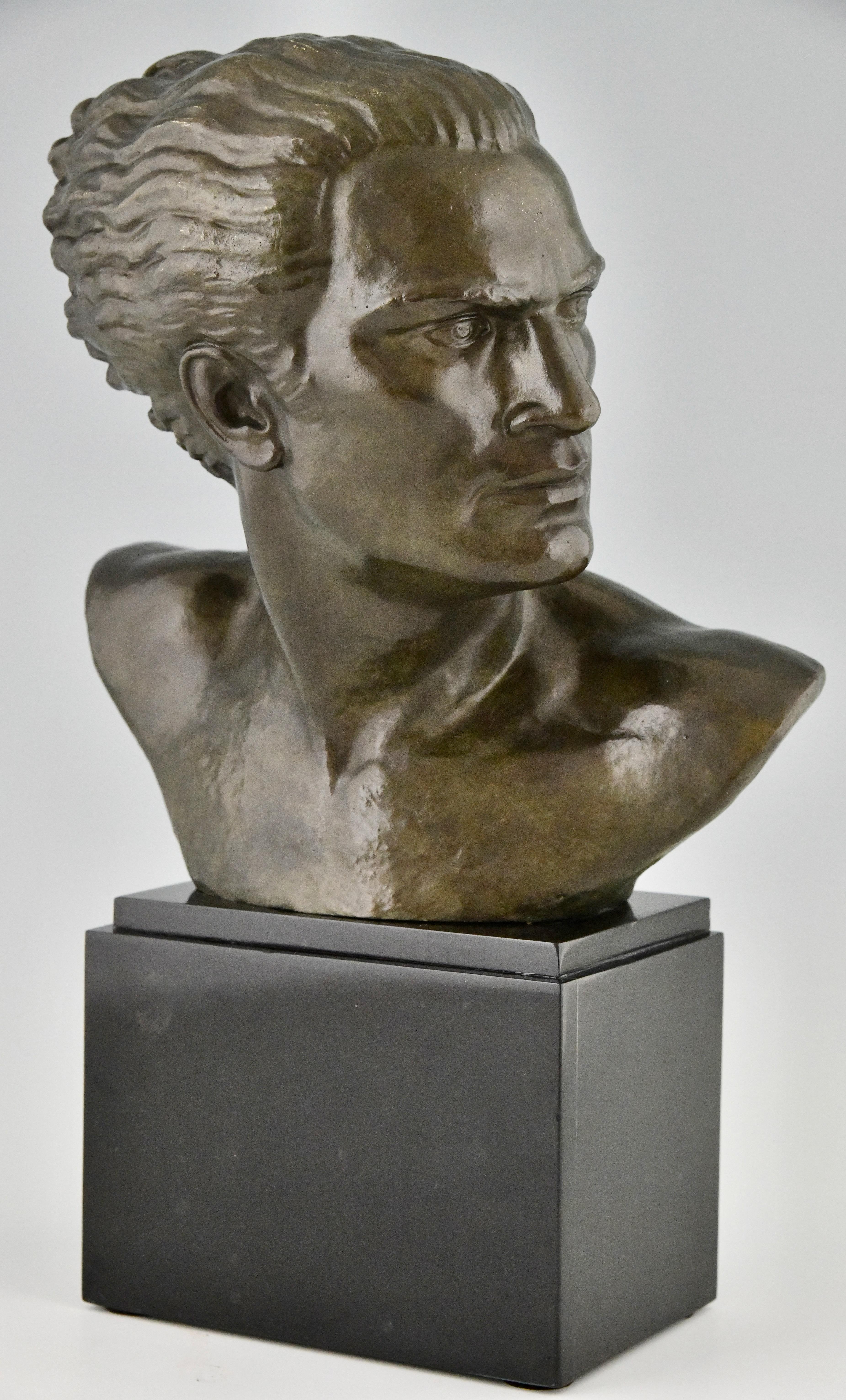 Escultura Art Déco en bronce de busto masculino del aviador Jean Mermoz, obra de Lucien Gibert. 
La escultura tiene una pátina verde y se alza sobre una base de mármol negro belga.
Francia 1925.
Un modelo similar se ilustra en u2028
Bronces,