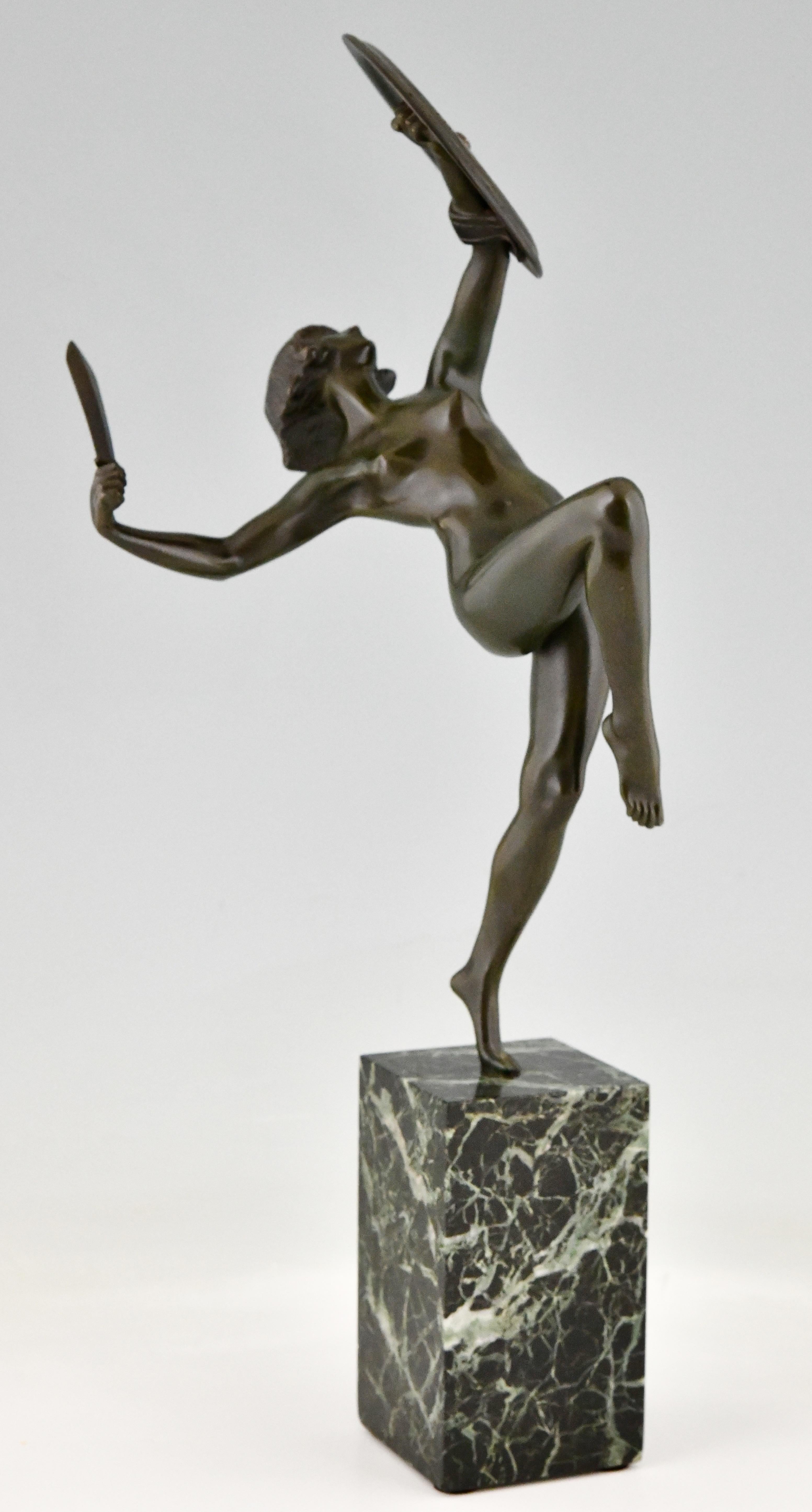 Art Deco bronze sculpture nude dagger dancer by Pierre Le Faguays, France 1930. Patinated bronze on green marble base. A female nude standing on one leg, holding a dagger in one hand. In her other hand she is holding a decorated shield. 
This