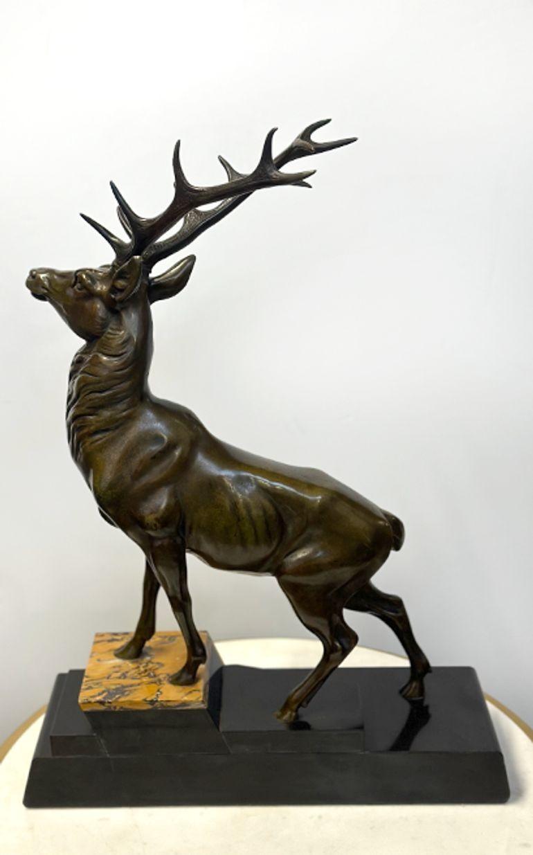 Enchanting Art Deco bronze sculpture depicting a deer standing gracefully on a two-tone marble plinth base. The texture and tone of the bronze bring this majestic creature to life, emphasizing its gentle yet alert demeanor.
Made in France, c.