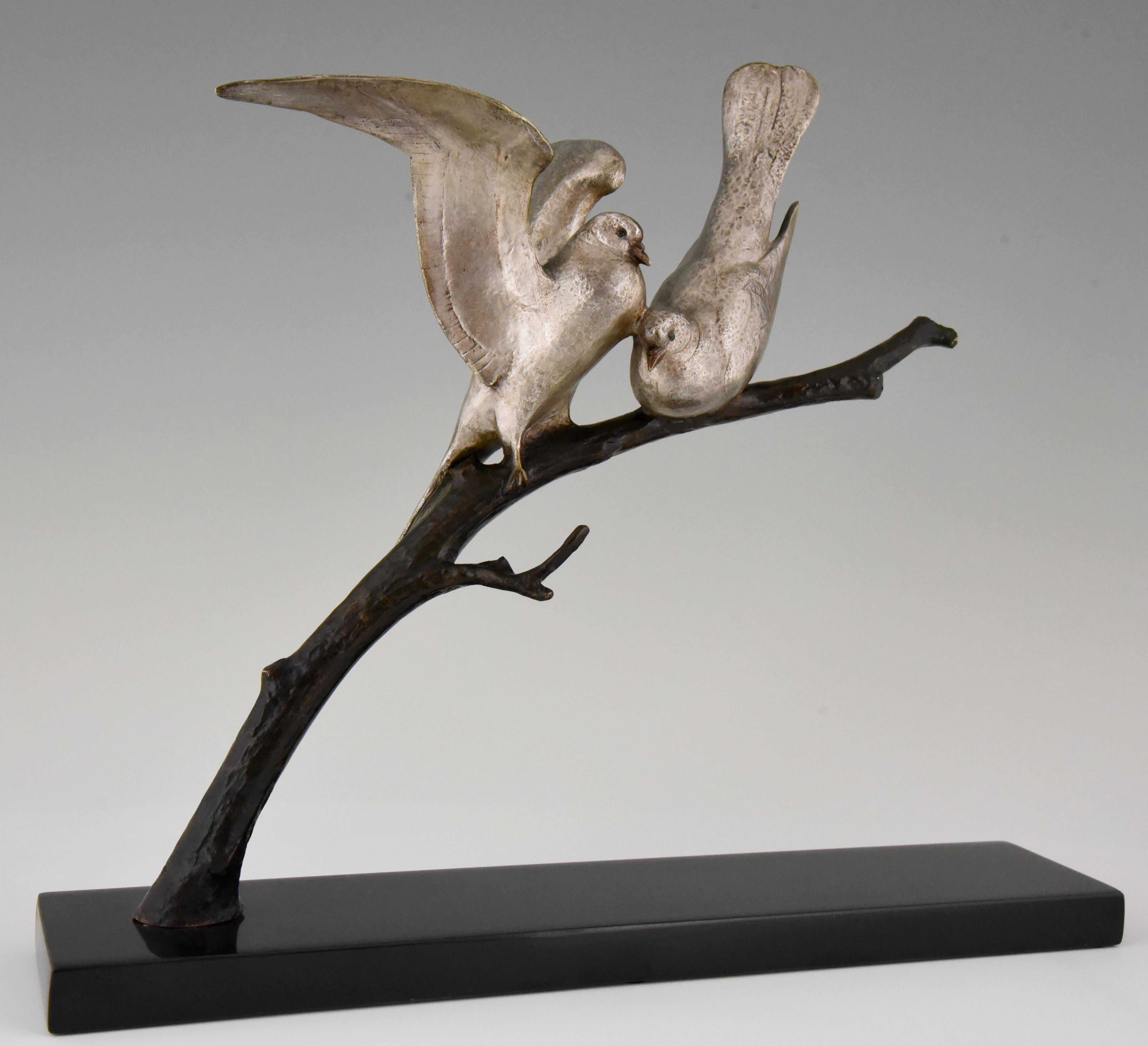 Lovely bronze Art Deco sculpture of two lovebirds sitting on a branch by the French sculptor Andre Vincent Becquerel. The bronze has a silver and brown patina and is mounted on a Belgian Black marble base. France circa 1930. 

This model is