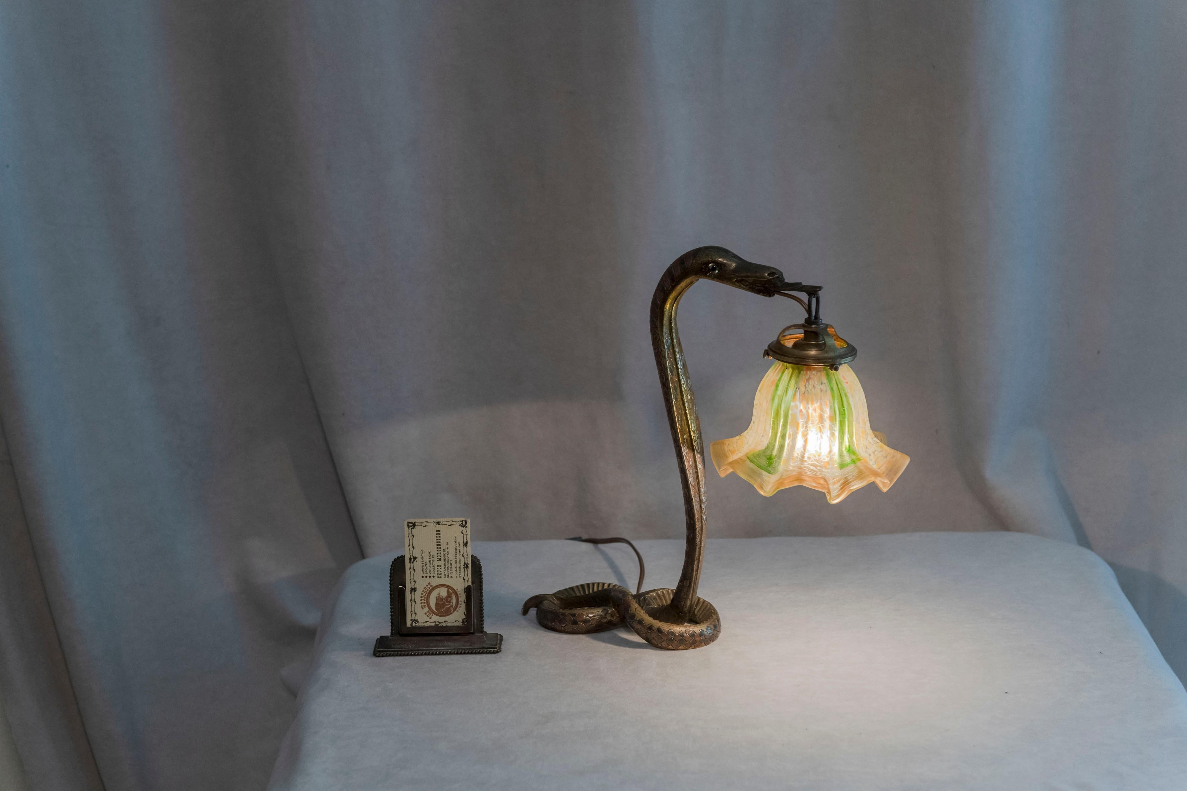 Cette lampe serpent en bronze offre certaines des caractéristiques les plus attrayantes. Le corps du serpent est assez détaillé avec de multiples couleurs en noir, cuivre et argent. Il convient de noter en particulier le motif complexe en relief de