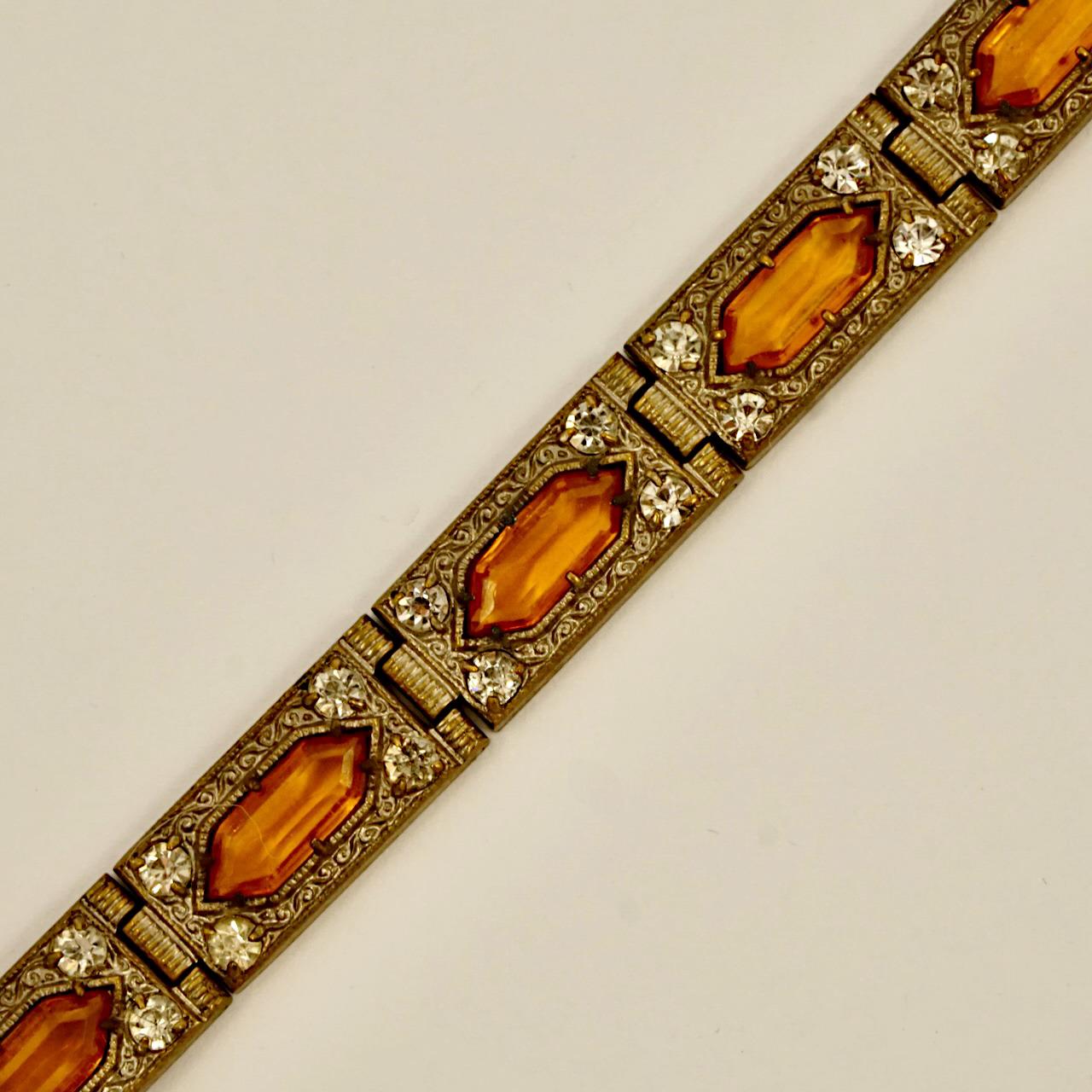 Elegante bracciale a maglie ornate in tonalità bronzo Art Deco, con pietre di vetro color ambra circondate da strass chiari. La chiusura funziona bene. Lunghezza 17,5 cm / 6,9 pollici e larghezza 9,5 mm / .37 pollici. Il bracciale era