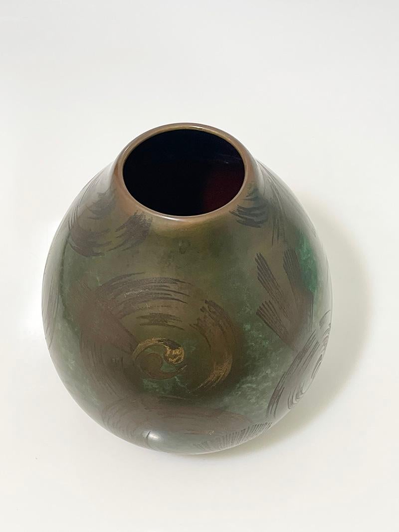 Art Deco bronze WMF Ikora vase by Paul Haustein, 1920s

An Art Deco bronze patinated vase by Paul Haustein for WMF Ikora, Germany, late 1920s
When light shines on the vase, the gold color will appear and gives the scroll pattern a beautiful shiny
