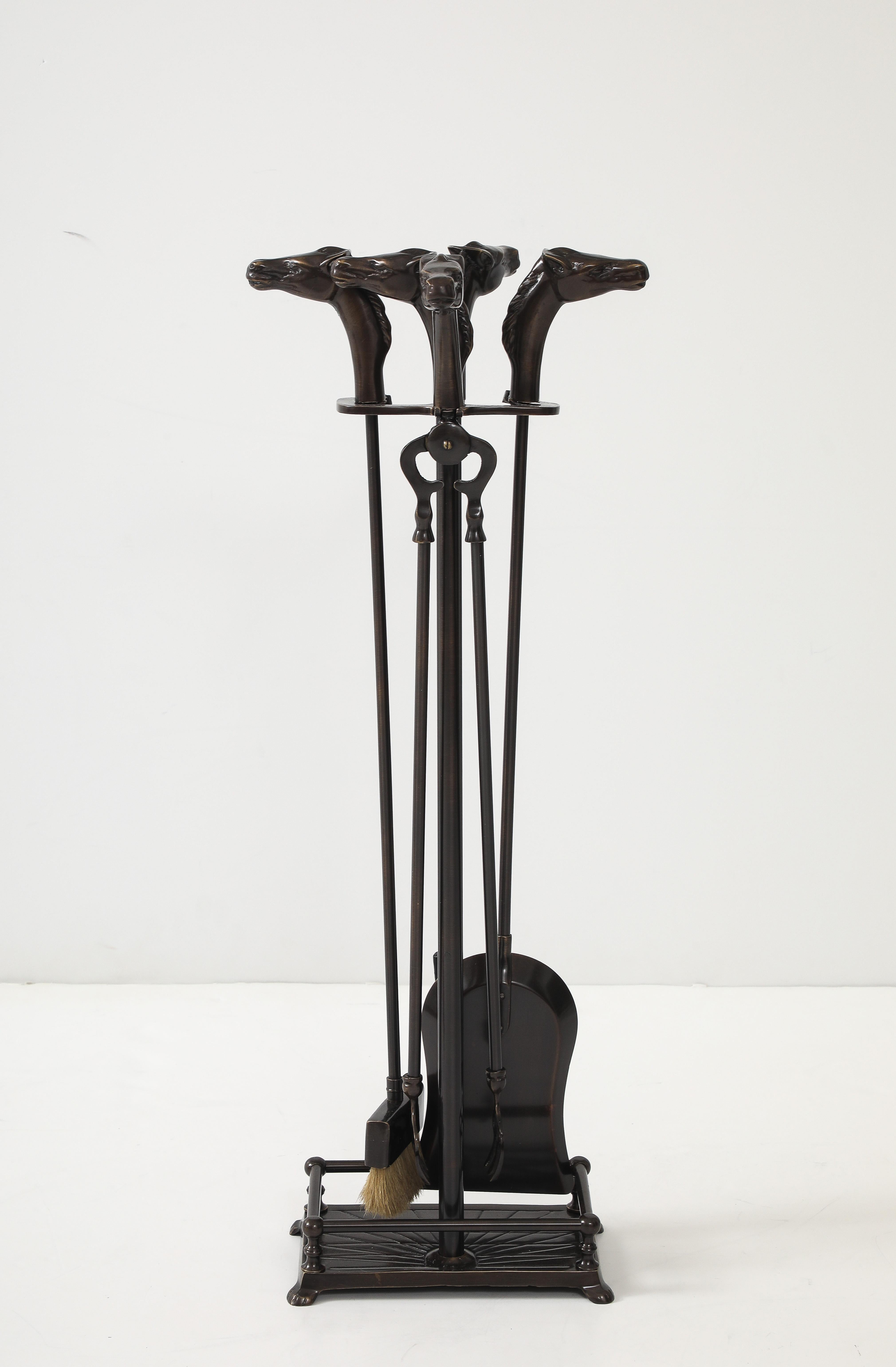 Fantastique ensemble d'outils à feu Art déco en bronze avec des embouts en forme de tête de cheval. 
L'ensemble comprend un tisonnier, une pelle, une pince, un balai et un support.