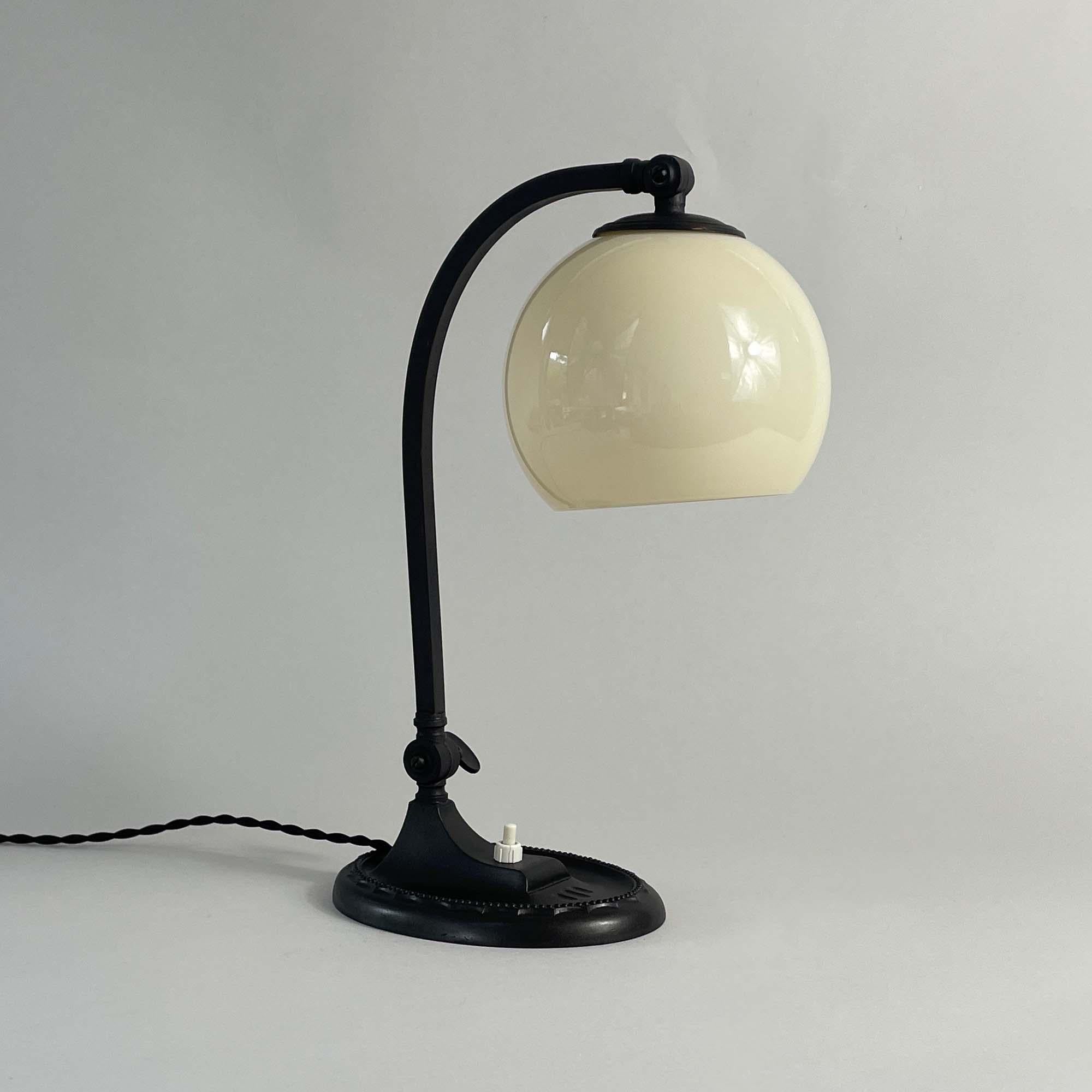 This Art Deco table lamp was designed and manufactured in Germany in the 1920s. It can be used as a table light as well as a piano lamp.

The lamp has a sleek, curved arm that supports the spherical shade, giving it a modern and elegant appearance
