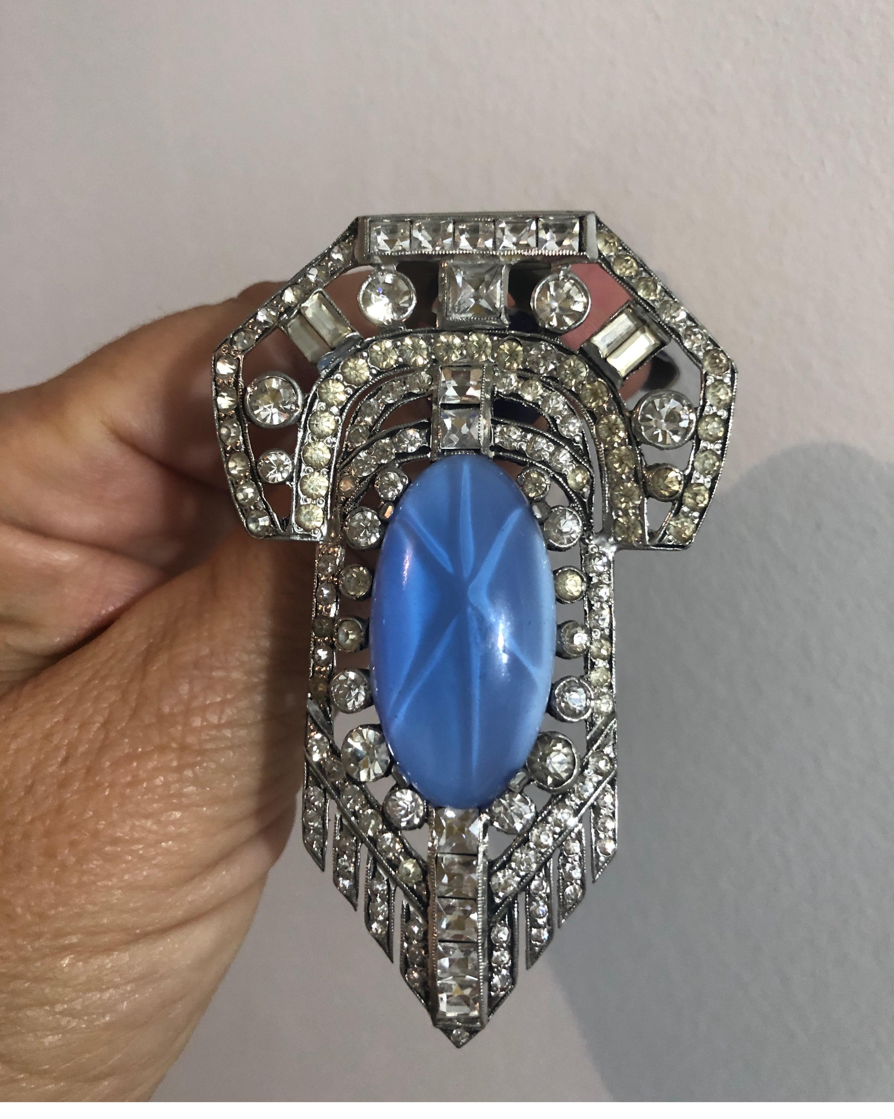  Spilla/ Fermaglio da cappotto in stile Art Deco. Caratterizzato da un grande occhio di gatto finto blu circondato da strass quadrati, rotondi e rettangolari. La maggior parte di esse sono vivacemente luminose. 3,12