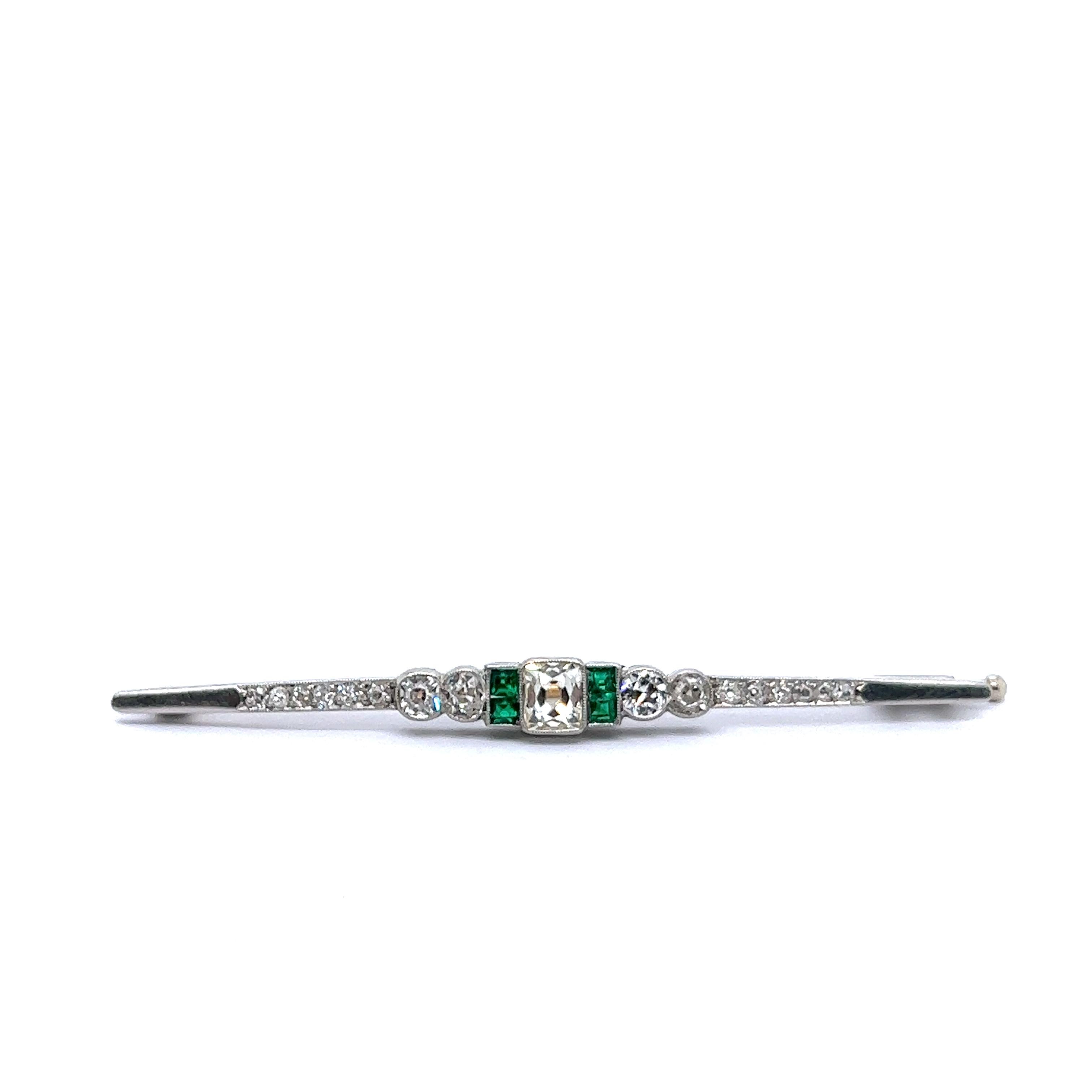 Introducing a stunning Art Deco pin brooch with diamonds and emeralds, a masterpiece of timeless elegance. 

This exceptional brooch seamlessly marries the warmth of 18 Karat yellow gold with the classic charm of white gold. It boasts a central
