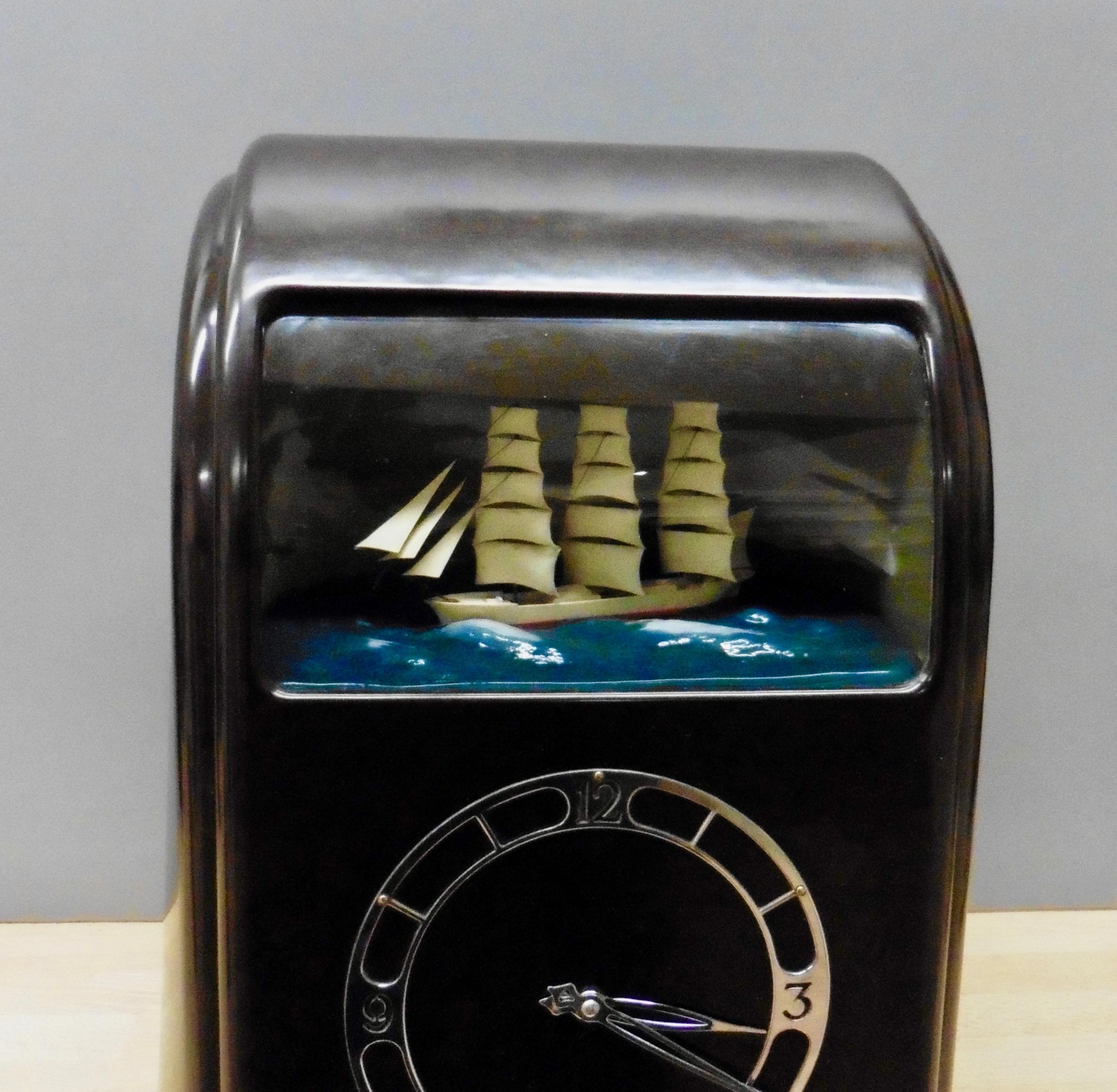 Art Deco Vitascope clock with automation rocking ship on an illuminated ocean scene with cloud background. Original ‘Art Deco’ Chrome hands with skeletonised dial. 

 Electric movement, ‘brown’ Bakelite case with original green painted back with