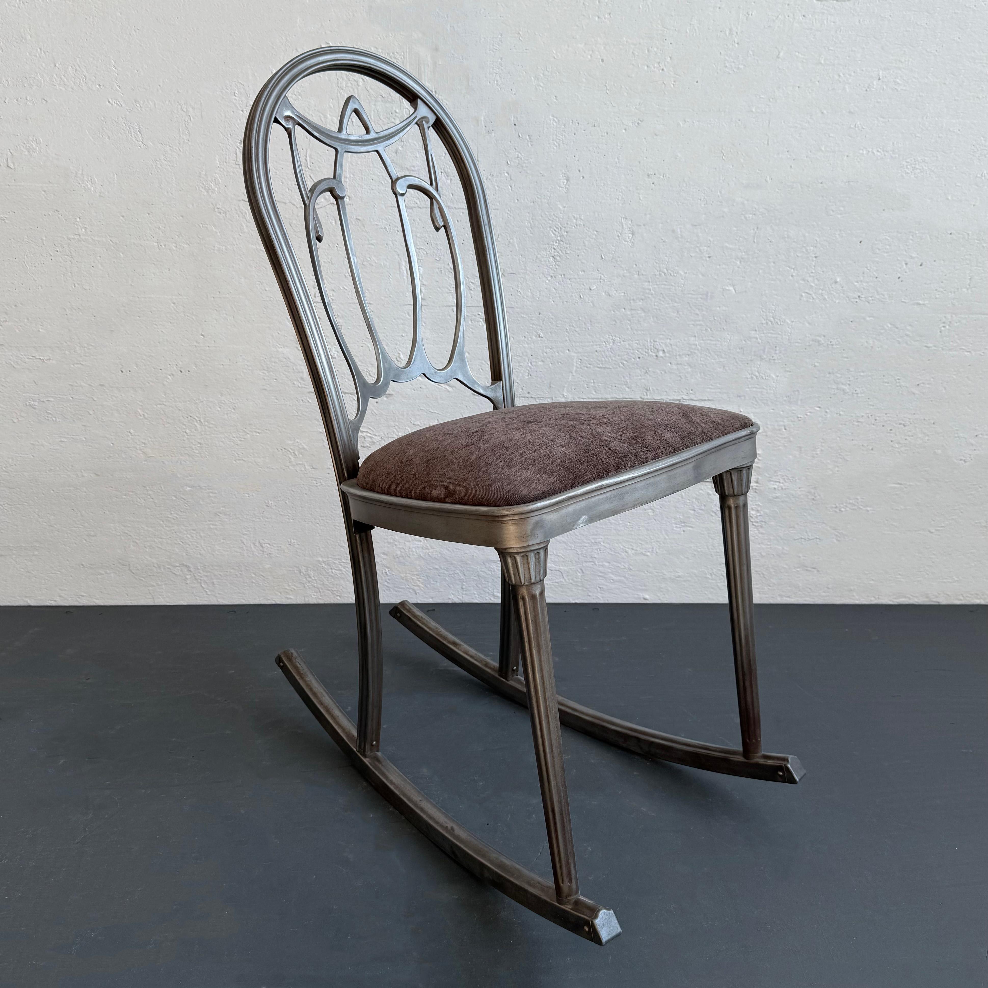 La sedia a dondolo art déco vintage dei primi del Novecento di The Doehler Metal Furniture Co. presenta una struttura in acciaio stampato e spazzolato con gambe scanalate e schienale a volute decorative. La seduta è stata rivestita di recente in un
