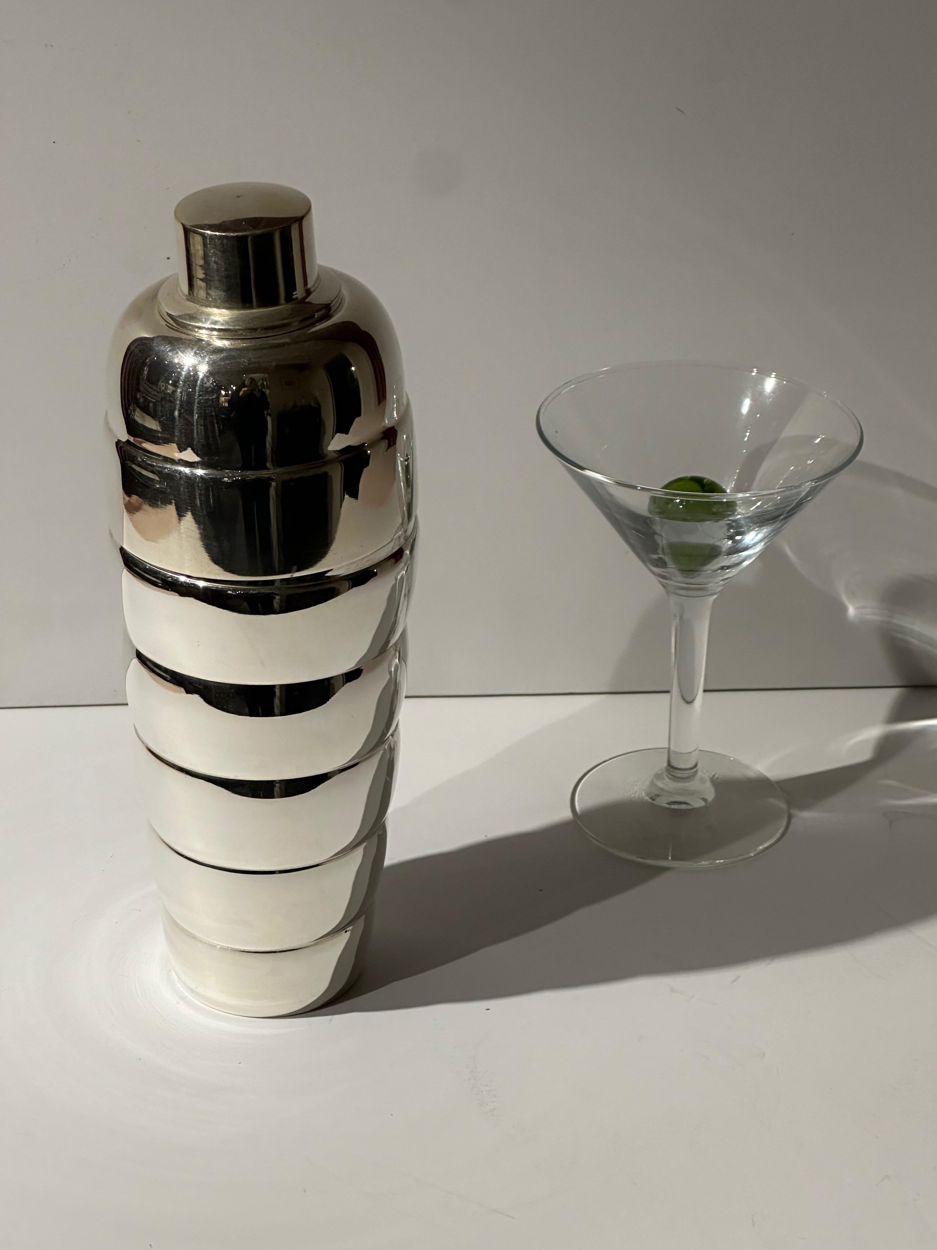 An Art Deco Cocktail Shaker with an unusual form a stack of bubbled and silver-plated shapes  that might remind one of the “Michelin Man” . Slightly taller than most shakers , it’s stepped design is graceful and sculptural… as well as perfectly