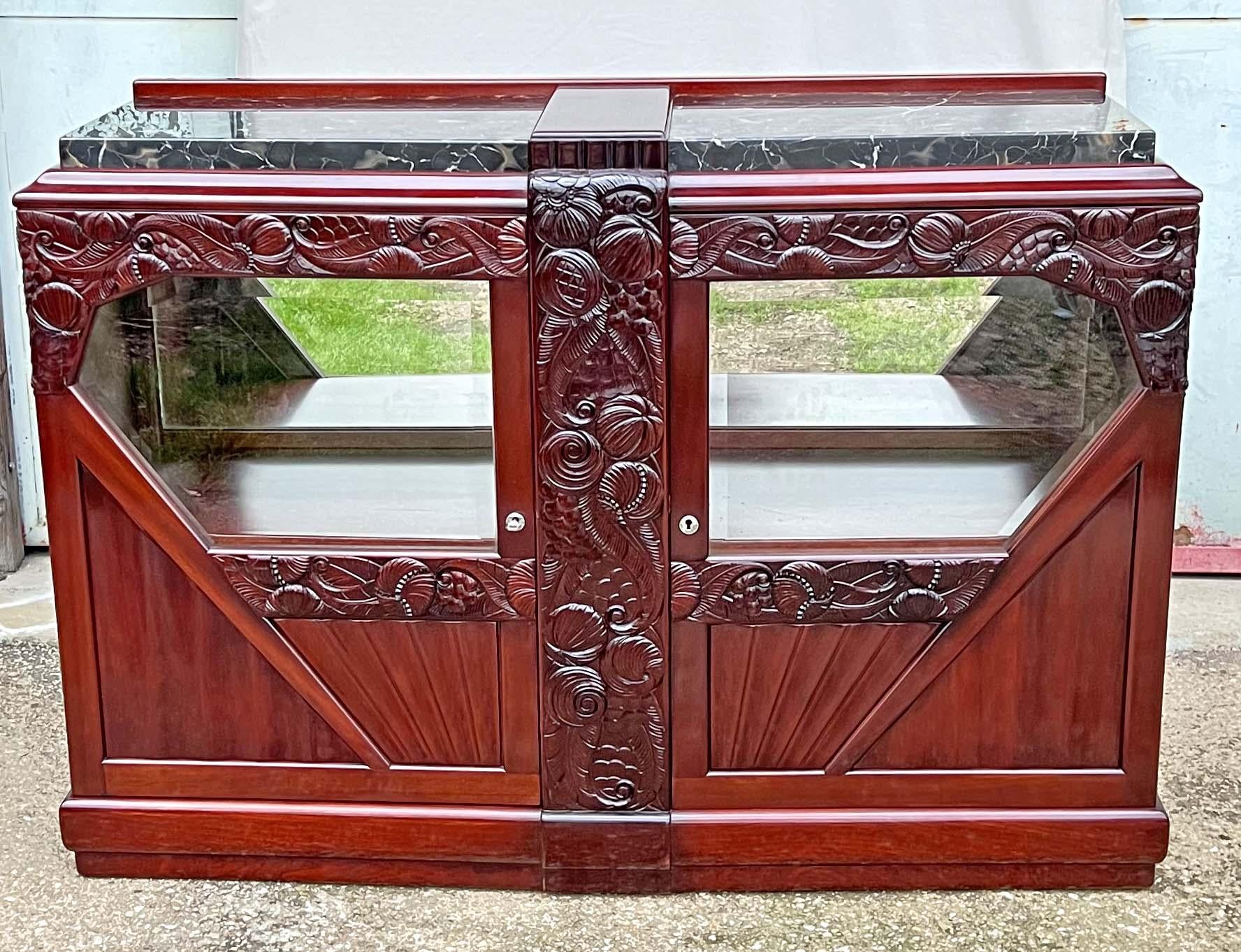 Art Deco buffet dating from around 1930, trapezoidal in shape, in a rosewood stained walnut, richly molded and carved with stylized floral patterns.

It opens with 2 doors with diamond panels.

Interior with miror, shelf mounted on rack.

The top in