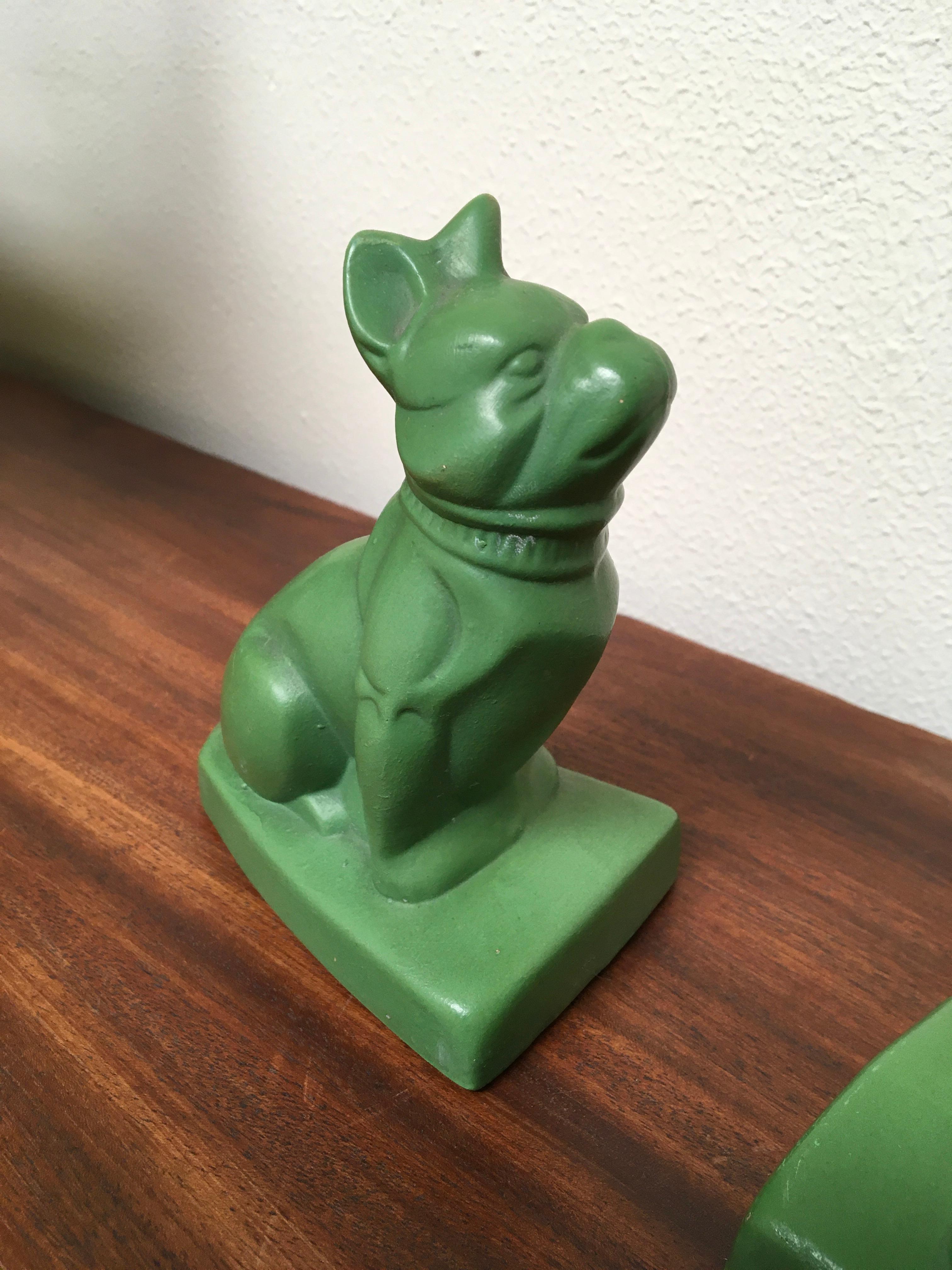 Art Deco bookends of French bulldog’s dogs.
This set of green pottery animal bookends has an abstract style, cubist design, Sphinx style.
They are sitting, heads up, ears up, waiting for someone. They also have a collar around the neck.
These