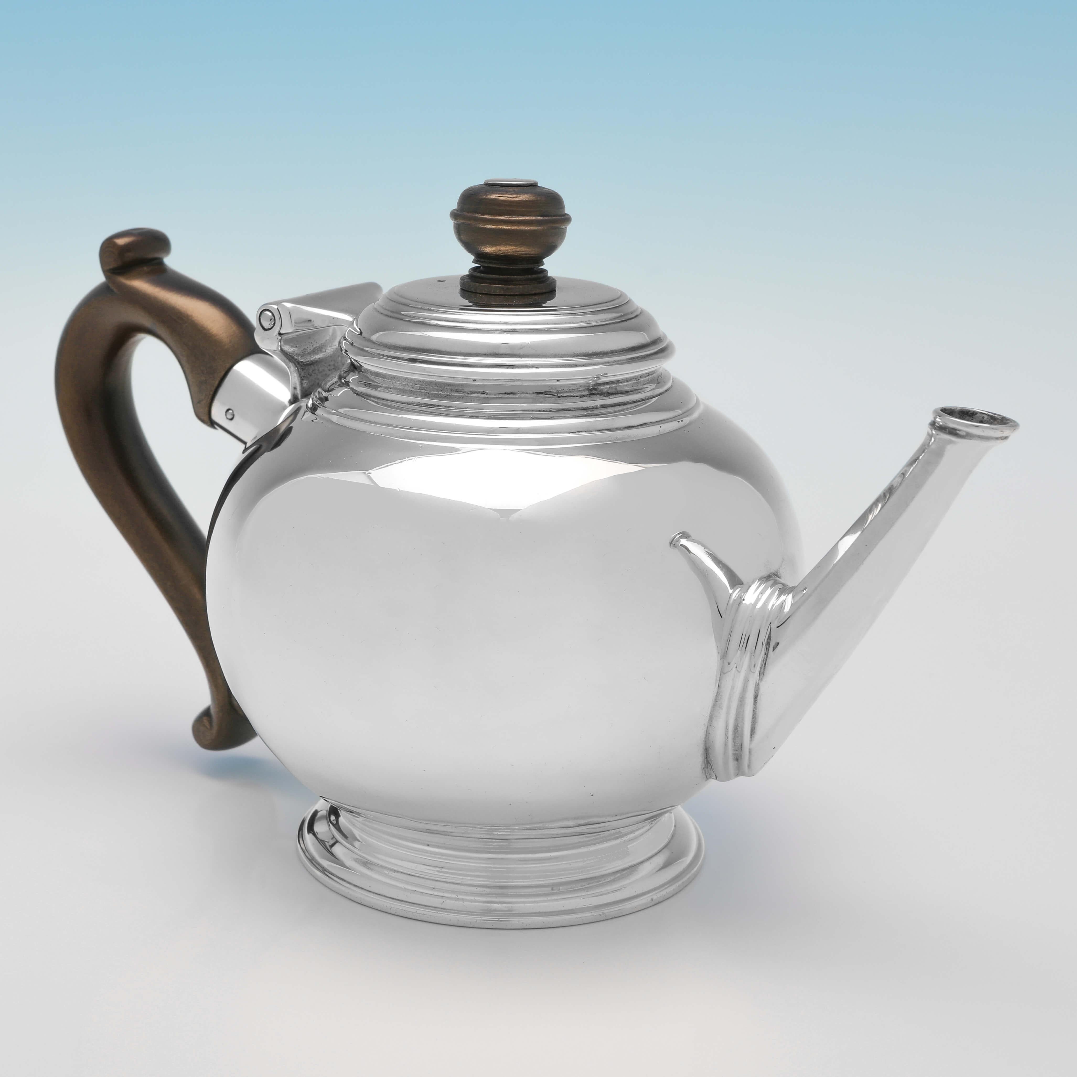 Hallmarked in London in 1929 by Richard Comyns, this very handsome, sterling silver teapot, is plain in style, and features a wooden handle and finial. The teapot measures 4.75