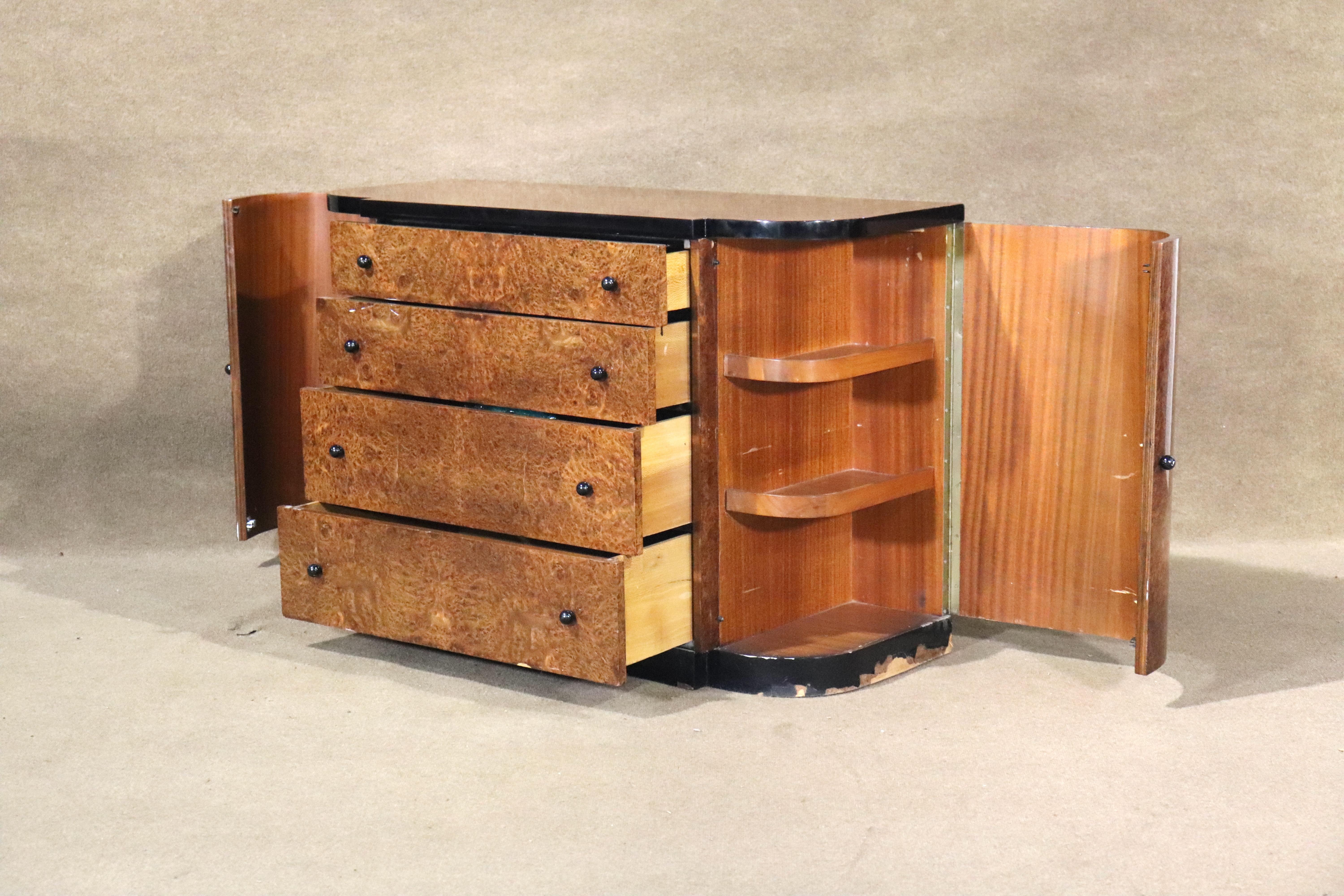Short Art Deco dresser in brilliant burled wood with black trim and hardware. Four wide drawers and two storage cabinets with shelving.
Please confirm location NY or NJ