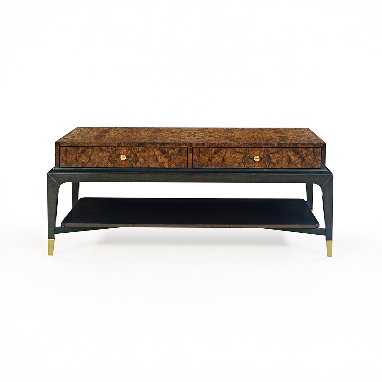 Son plateau rectangulaire, fabriqué dans un placage de ronce de noyer naturel, présente des motifs de grain complexes qui évoquent une élégance intemporelle. Quatre tiroirs sont subtilement intégrés pour le rangement, tandis que les poignées rondes