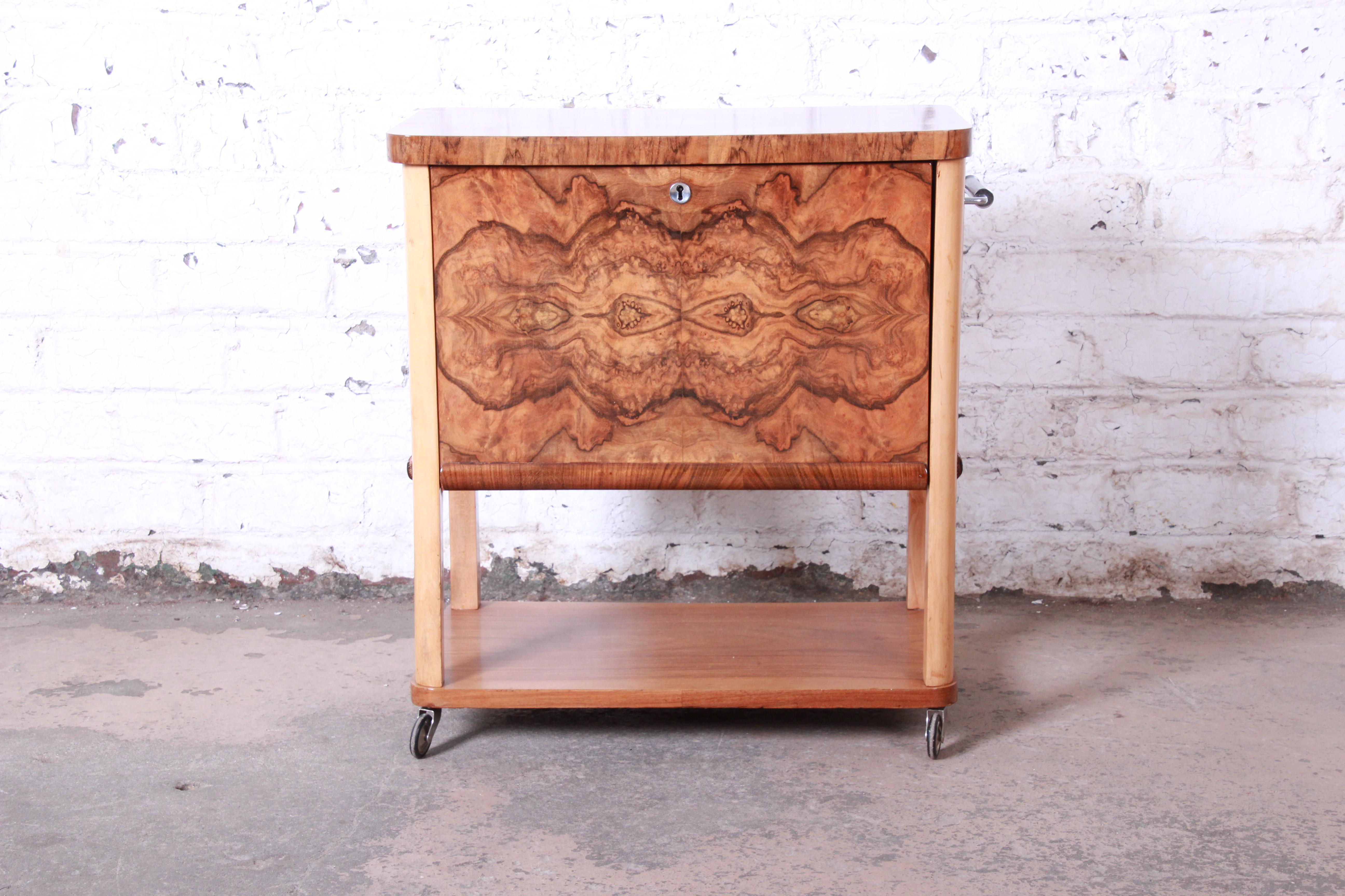 A unique and exceptional Art Deco burl wood bar cart. The cart features stunning burl wood grain, and it is finished on all sides. It has a flip-up top and drop-down side, and the interior cabinet offers good storage for liquor and barware. It sits