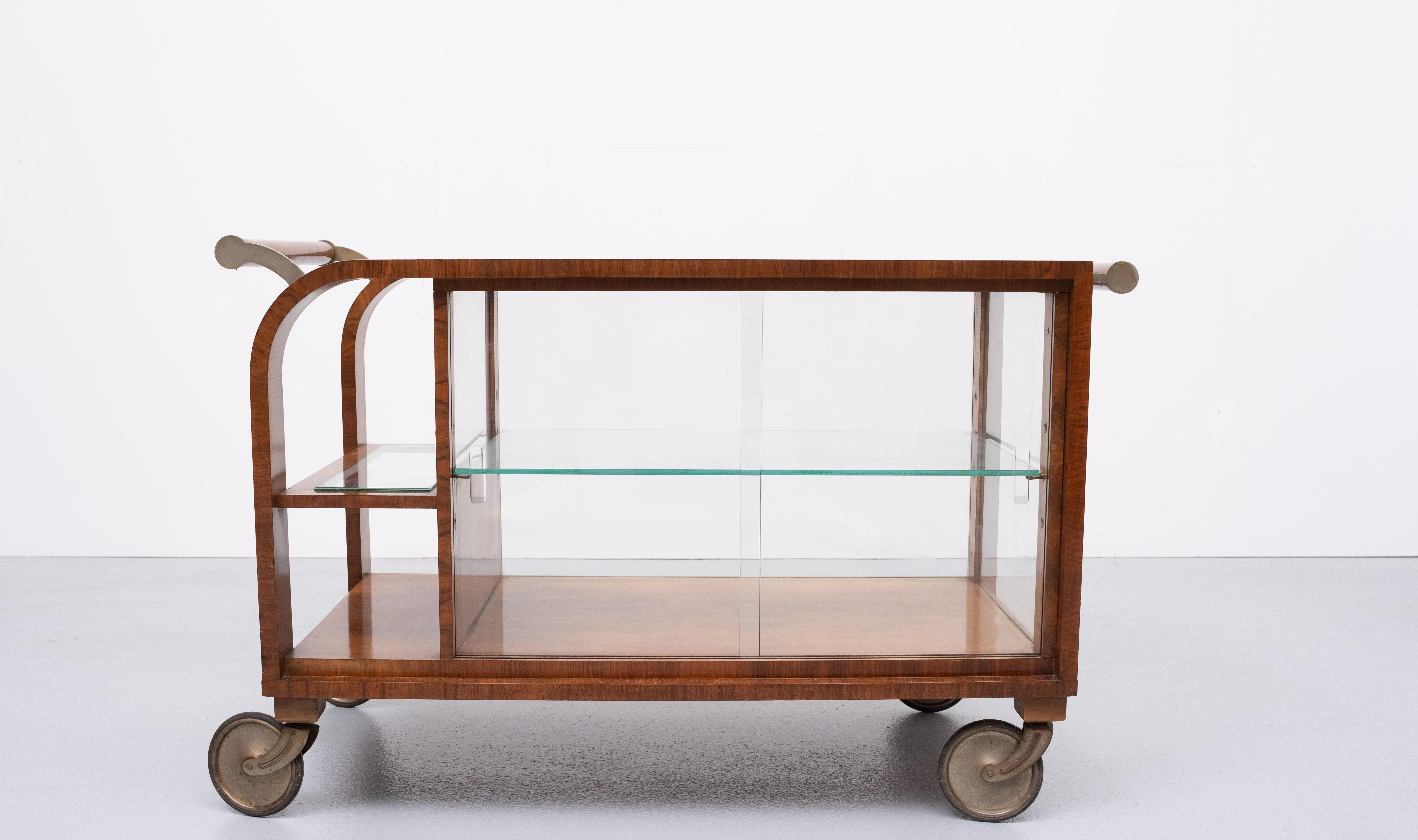 Superb curved Art Deco bar card or bakery table. Burl wood, comes on nickel wheels. The round carrot nuts handle bars are mounted in hand made Nickel holders comes complete with all the glass ware.
Two sliding glass doors. Glass top and shelves