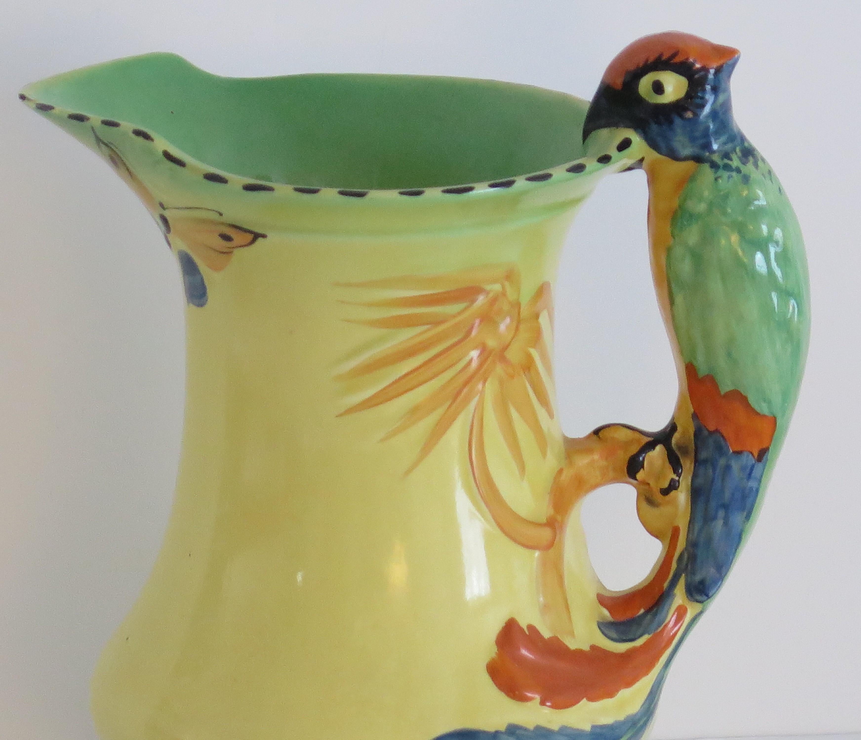 This is a very decorative Burleigh Ware pottery jug or pitcher made by Burgess and Leigh of Burslem, Staffordshire Potteries, England during the Art Deco period, circa 1930's.

The jug has an interesting shape with a very interesting Parrot loop