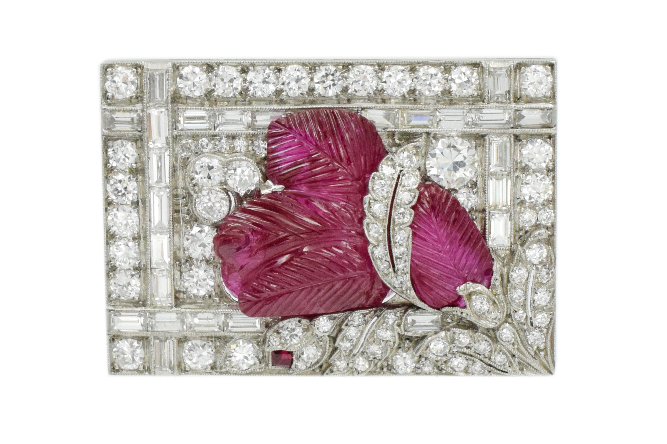 Impressive, Burmese ( Myanmar) carved  ruby & diamond brooch.

The brooch is designed as a pave-set plaque of rectangular outline , enhanced with foliate motifs, centering a carved ruby, with baguette cut diamond trim.
Accompanied by AGL report,