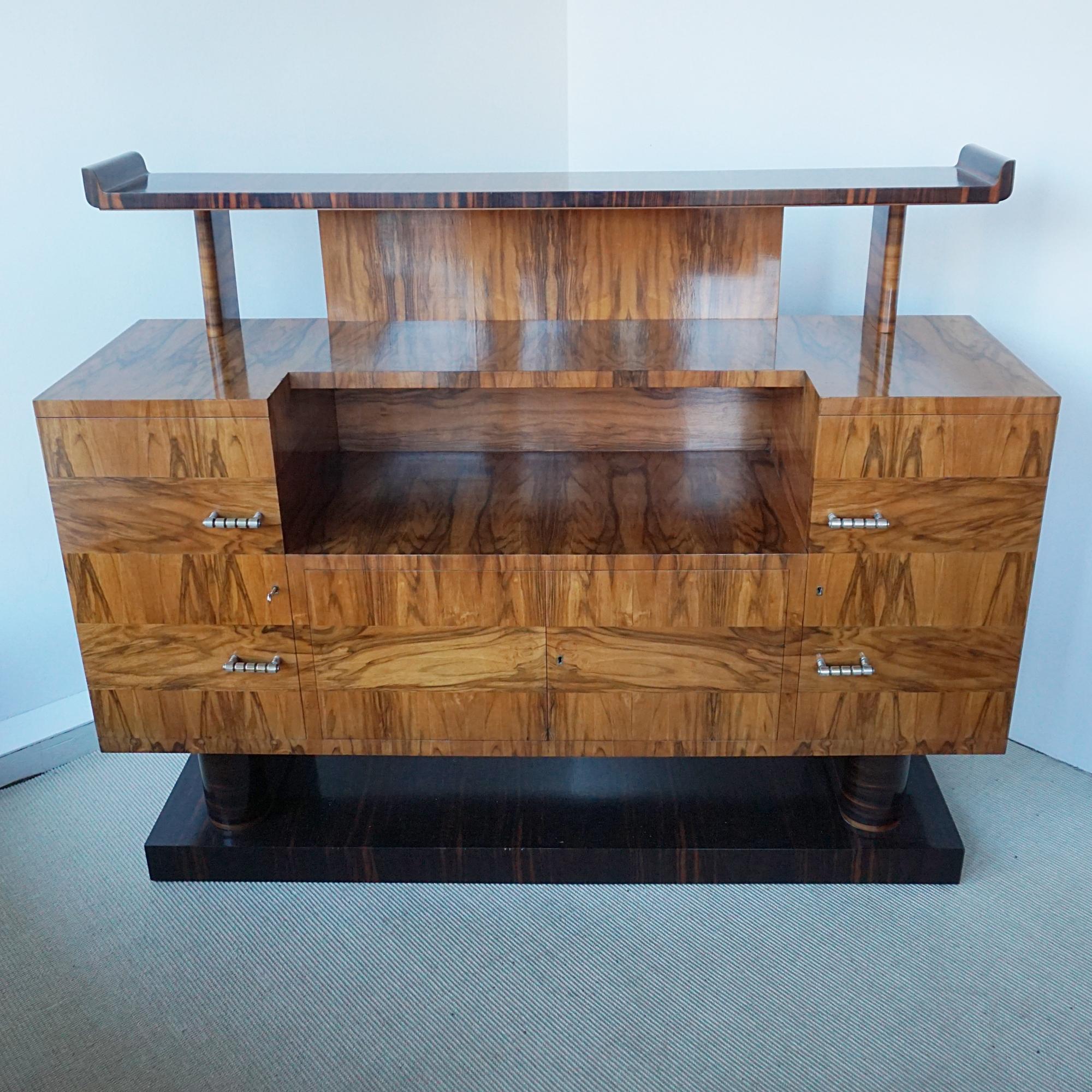 Buffet Art Déco à deux niveaux. Plaqué en ronce de noyer avec une étagère supérieure en ébène de macassar surmontant une section centrale ouverte avec deux portes d'armoire de chaque côté s'ouvrant pour révéler un intérieur à étagères avec une
