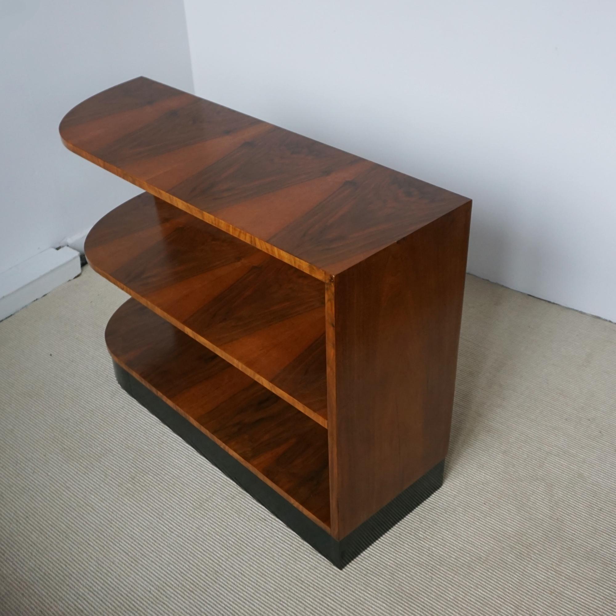 An Art Deco open bookcase. Burr walnut veneered with a curved edge and ebonised base.  Veneered to back.

Dimensions: H 72.5cm W 105cm D 35cm Aperture of shelves from Bottom H 26.5cm H 29.5cm 

Origin: English

Date: Circa 1935

Item Number: