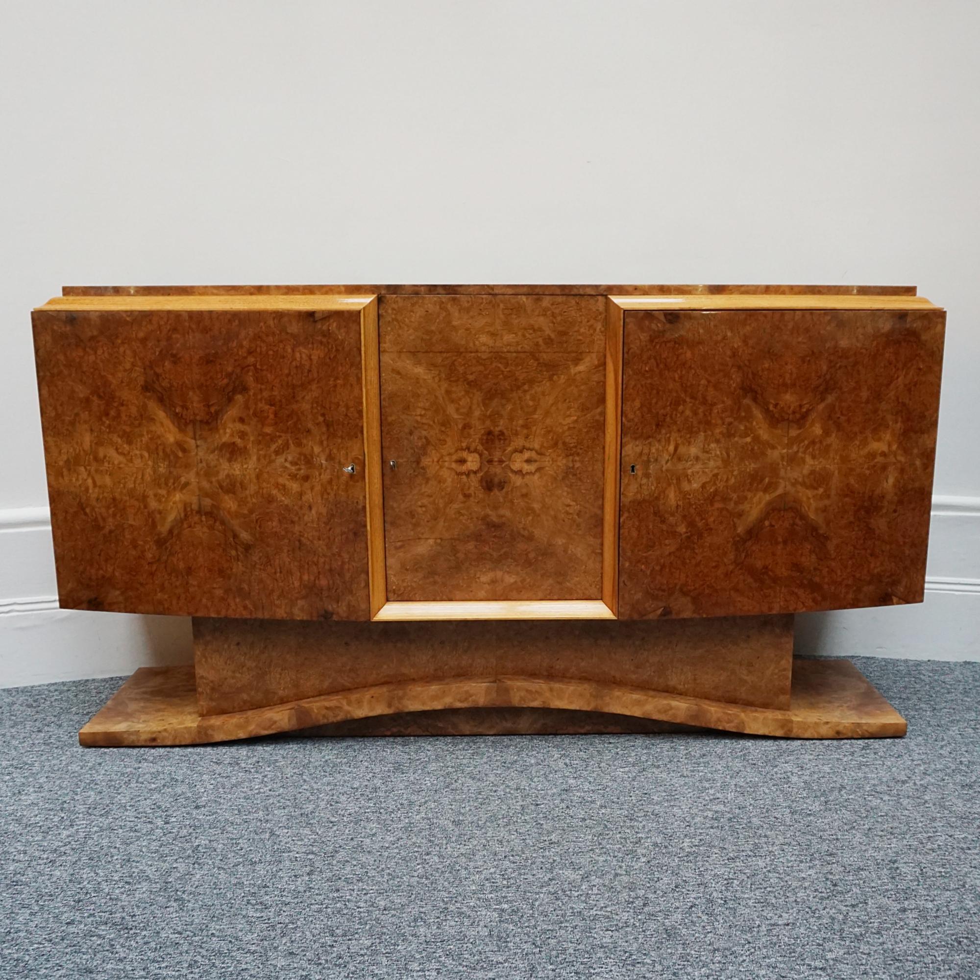 An Art Deco Sideboard by Hille. Burr walnut veneered with integral shelving and pull out drawers as well as a cocktail compartment. Set over a curved stepped base. 

Dimensions: H 97.5cm, W 183cm, D 51cm 

Origin: English

Date:  circa 1935

Item