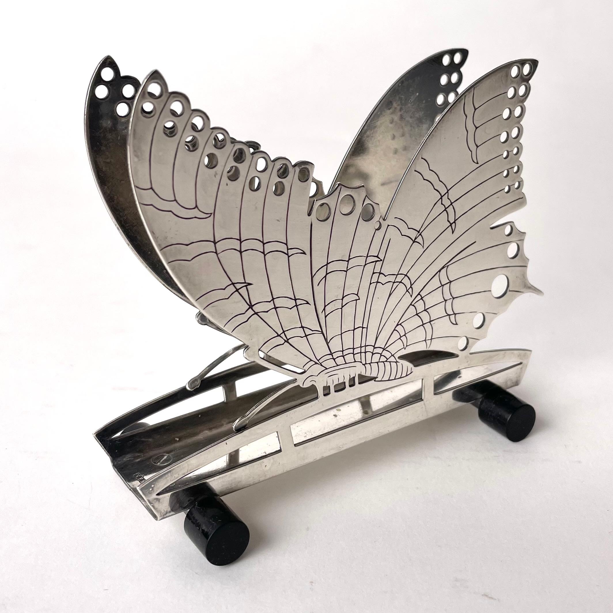 Charming Art Deco Butterfly Napkin Holder Nickel Silver and Bakelite, 1920s-1930s

This charming napkin holder is both functional and decorative. It takes the shape of a butterfly in a quite unusual pose, standing rather than in flight. The creature