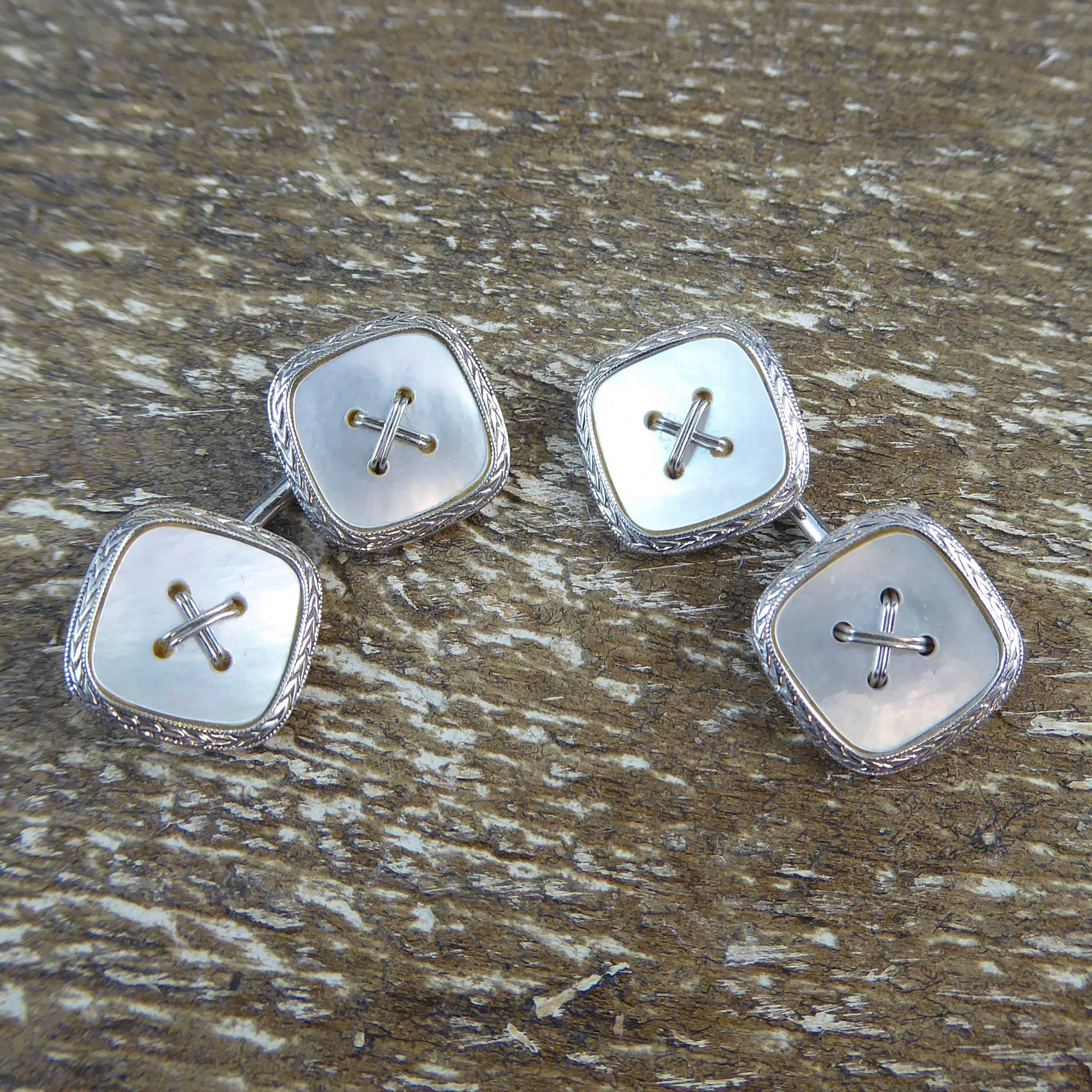 Art Deco cufflinks in a button style.  A rounded square shape of mother-of-pearl sits within a white gold border that has been given a pointed arrow design within millegrain edge.  To the centre of the mother-of-pearl there is white gold 