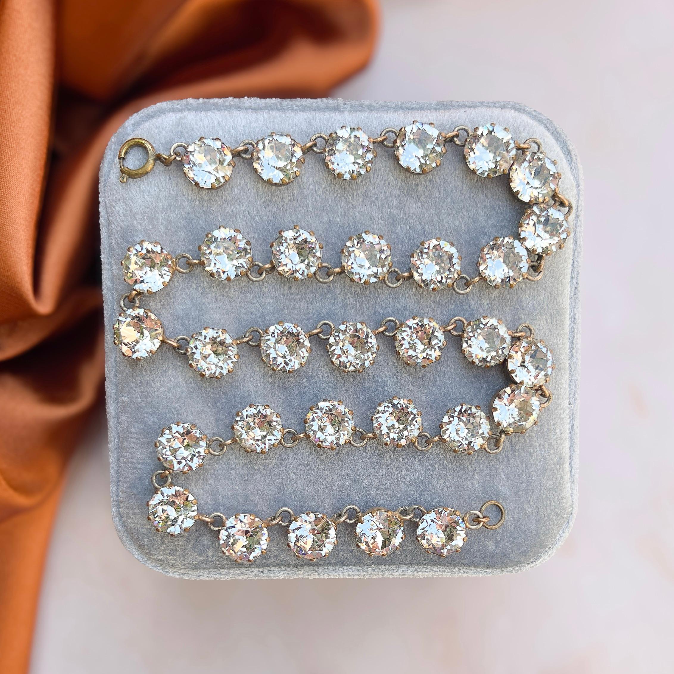 This stylish necklace was created in c.1930. 

Condition Report:
Excellent

The Details...
This necklace is constructed from gilded metal. It is detailed along its length with large, round, colourless paste stones. All of these stones are