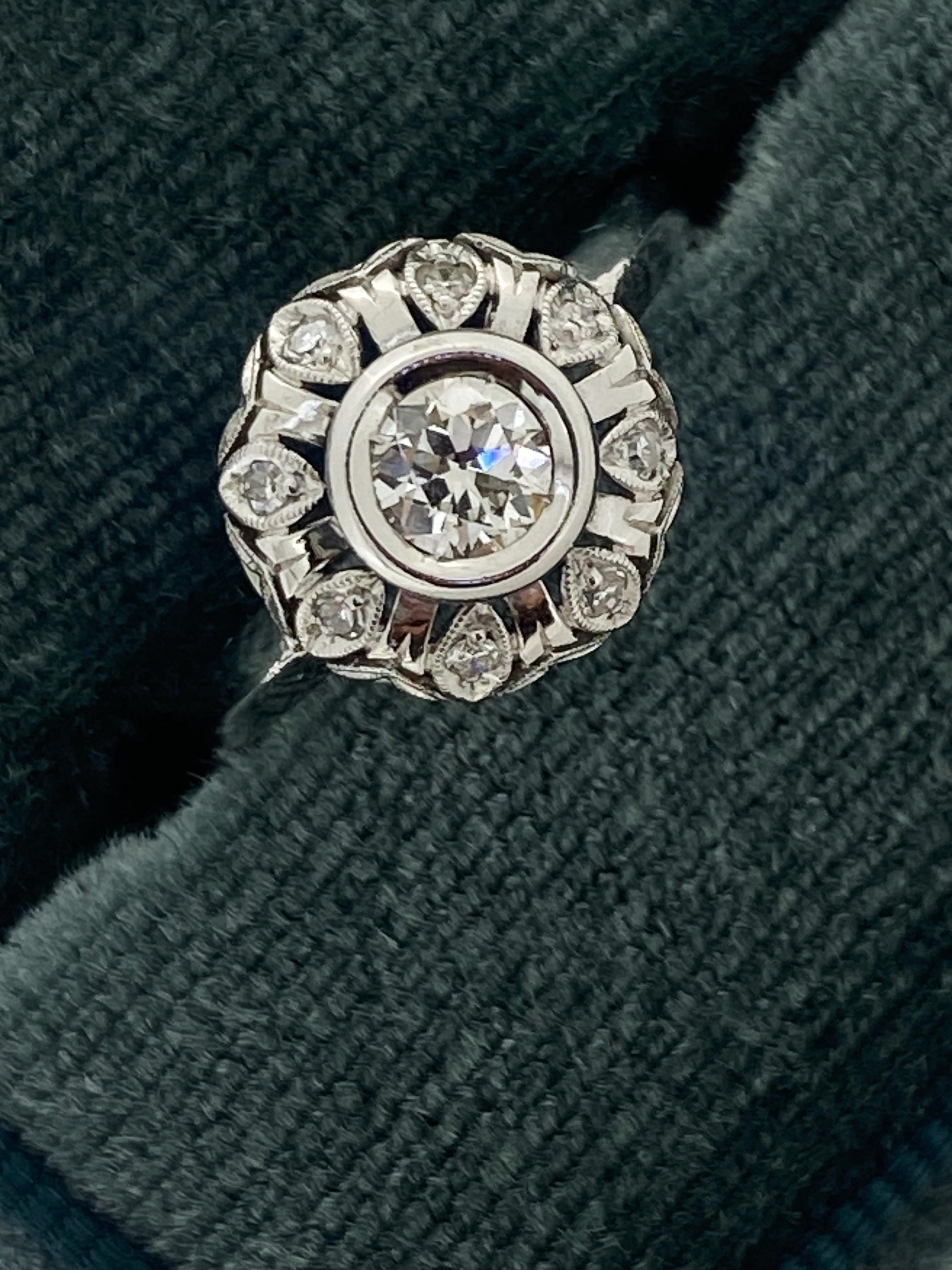 Dieses visuell auffällige Original-Schmuckstück im Art-Deco-Stil
ist aus 18K Weißgold gefertigt
mit bemerkenswerter Aufmerksamkeit für Details:

Entworfen als bauchiger Stil-Cluster, 
der Ring ist mit einem auf der Erde abgebauten Diamanten im