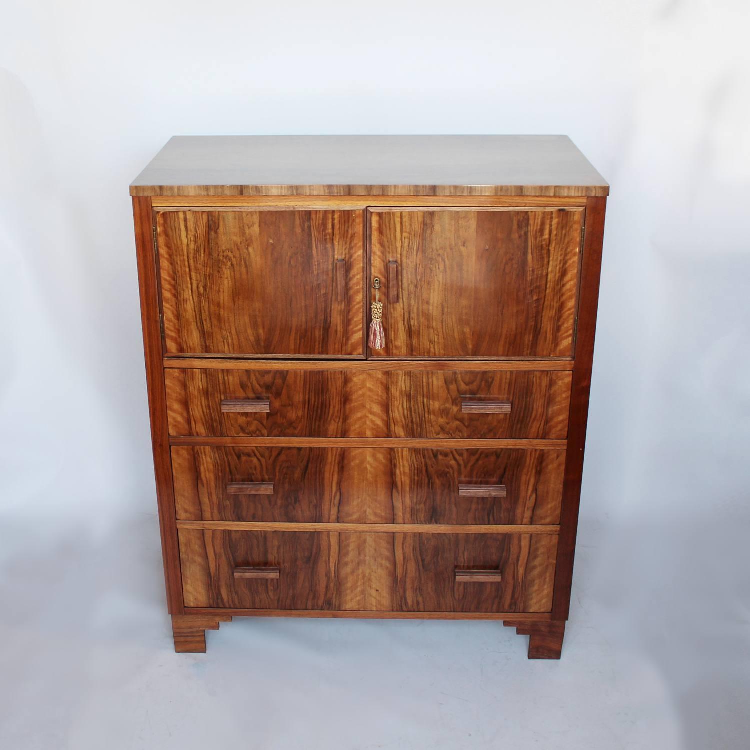 An Art Deco cabinet chest. Three lower drawers with two-door cabinet to top. Walnut throughout with original wooden handles.

 