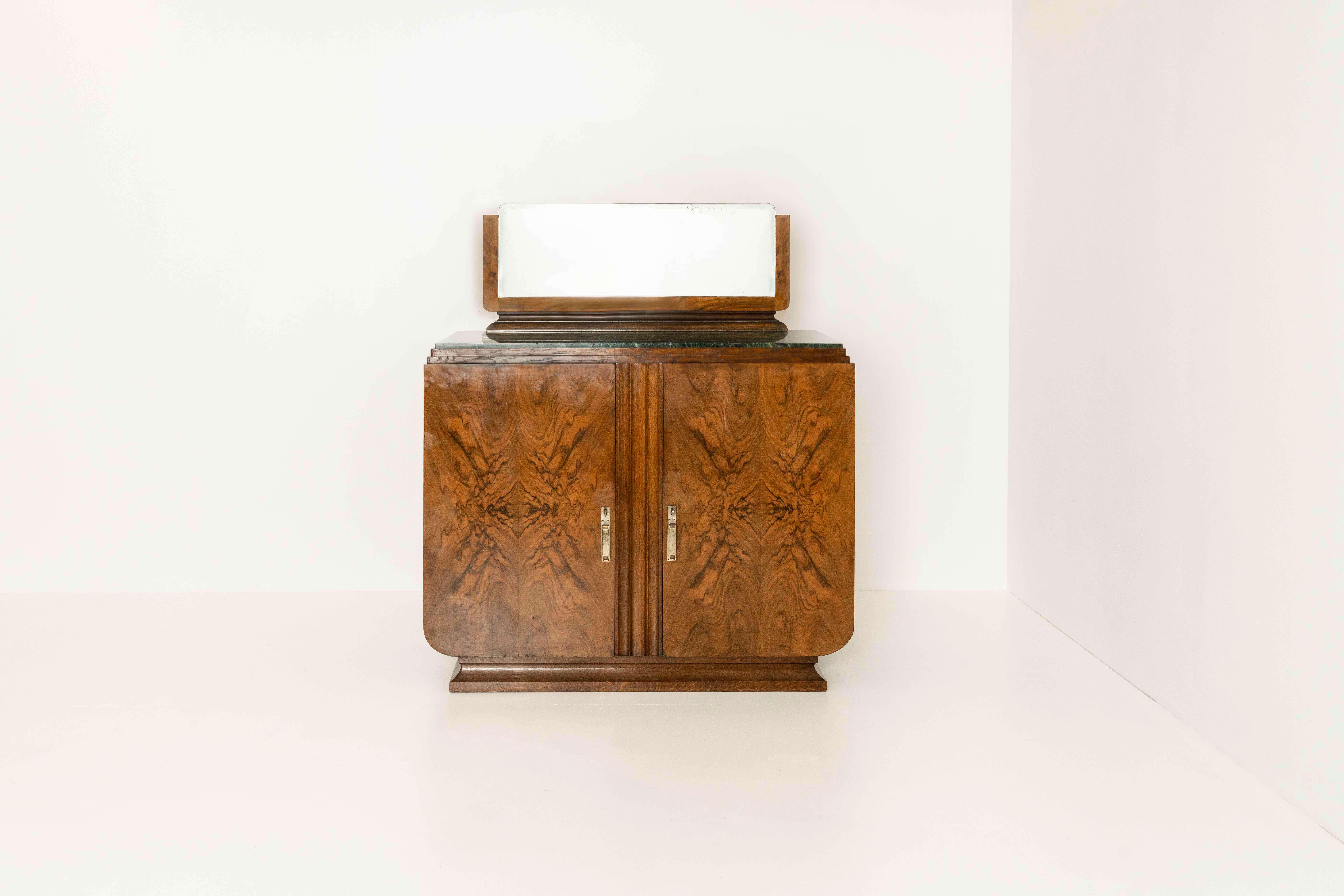 Nice Art Deco cabinet in mirrored mahogany with a marble top and mirror. The cabinet has a very attractive design with the cabinet resting on a base and giving it a beautiful shape. The top is made of green marble. The cabinet has two shelves and