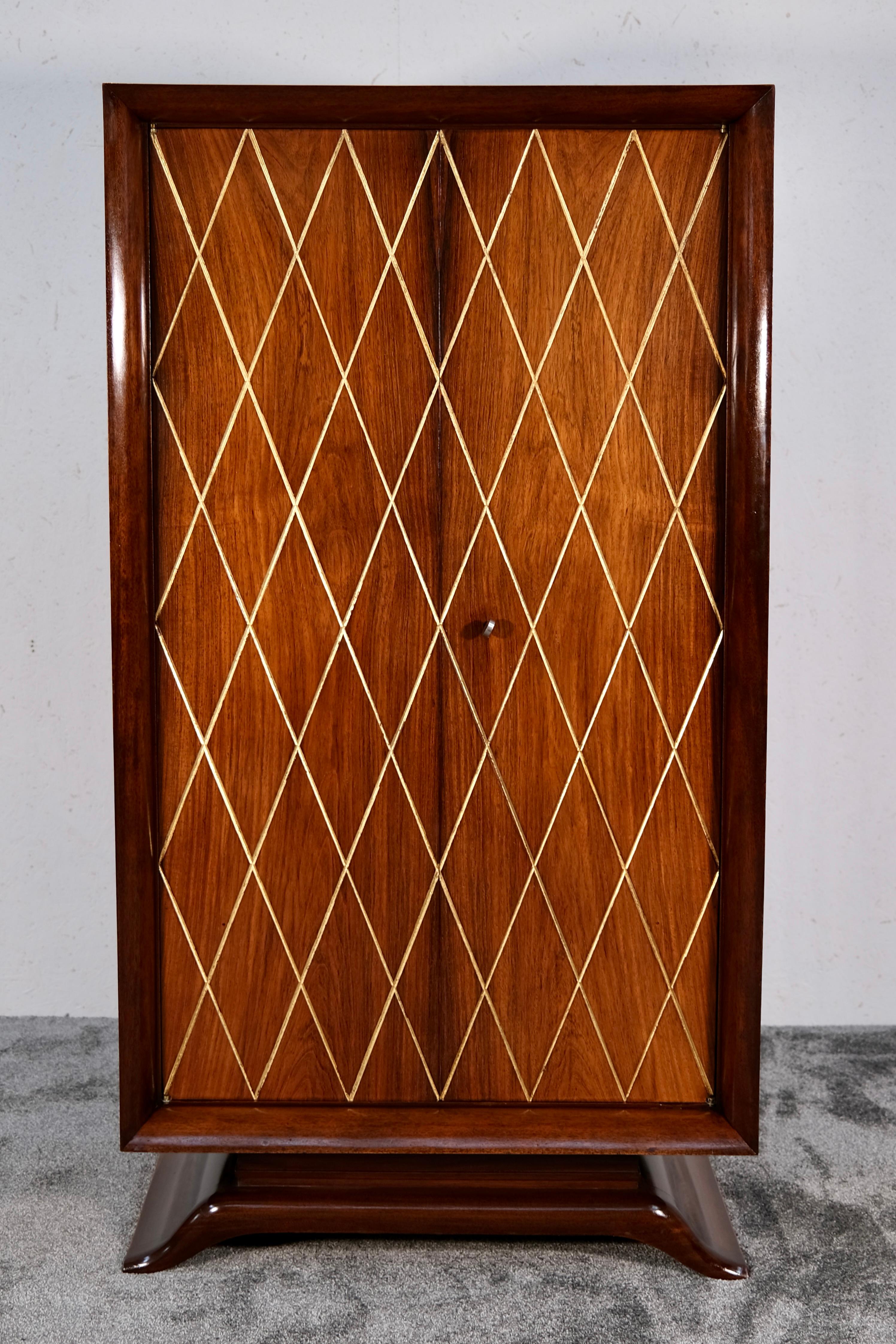 Aporta elegancia atemporal y presencia escultórica a tu interior con este impresionante armario Art Déco de madera de nogal, fabricado en Francia en la década de 1930. Esta pieza de almacenaje de dos puertas, verdadera expresión del refinado diseño