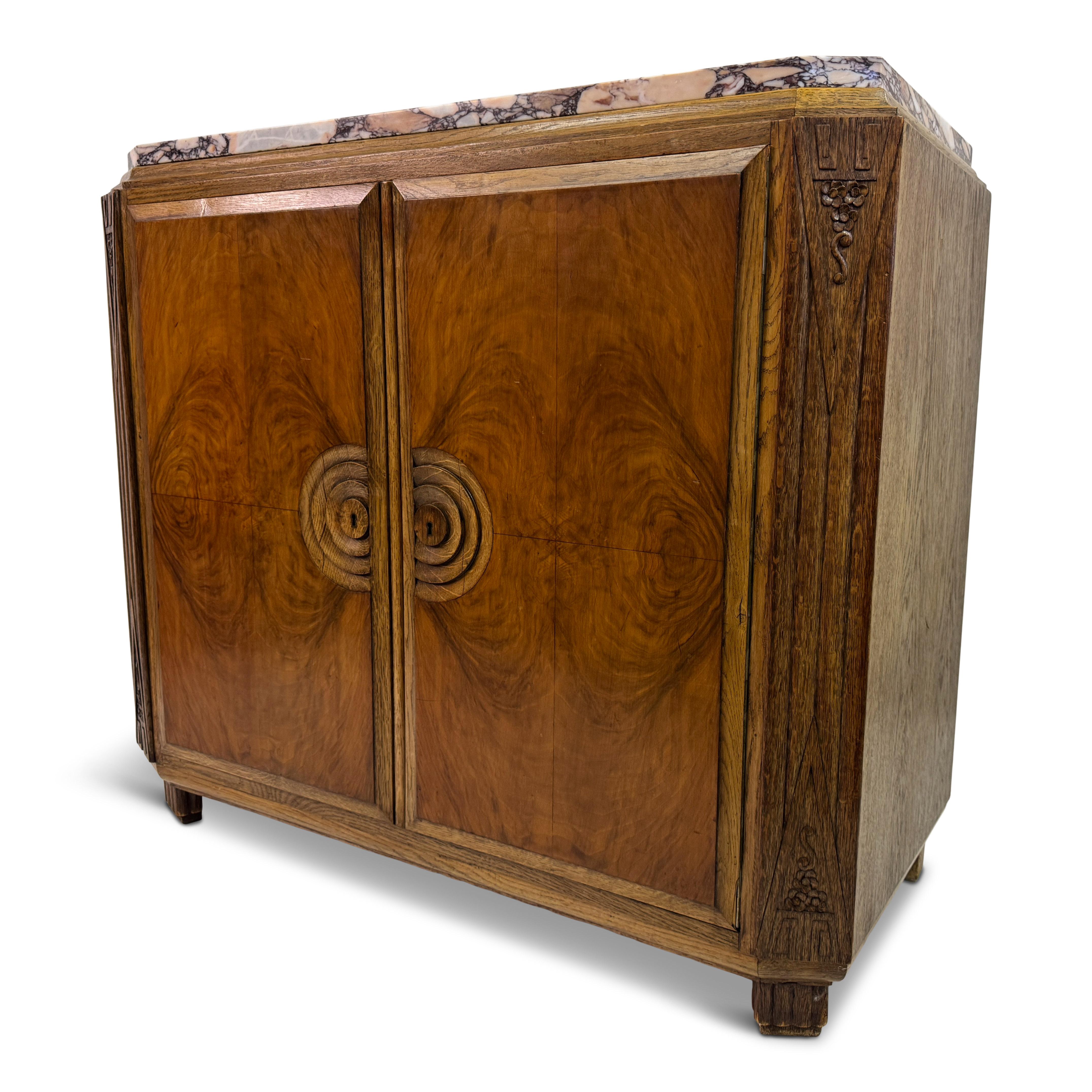 Art Deco Cabinet with Marble Top, France, 1930s


A fine French Art Deco cabinet, dating to the 1930s, distinguished by its geometric silhouette and striking use of materials. The body is veneered in richly figured walnut, the book-matched doors