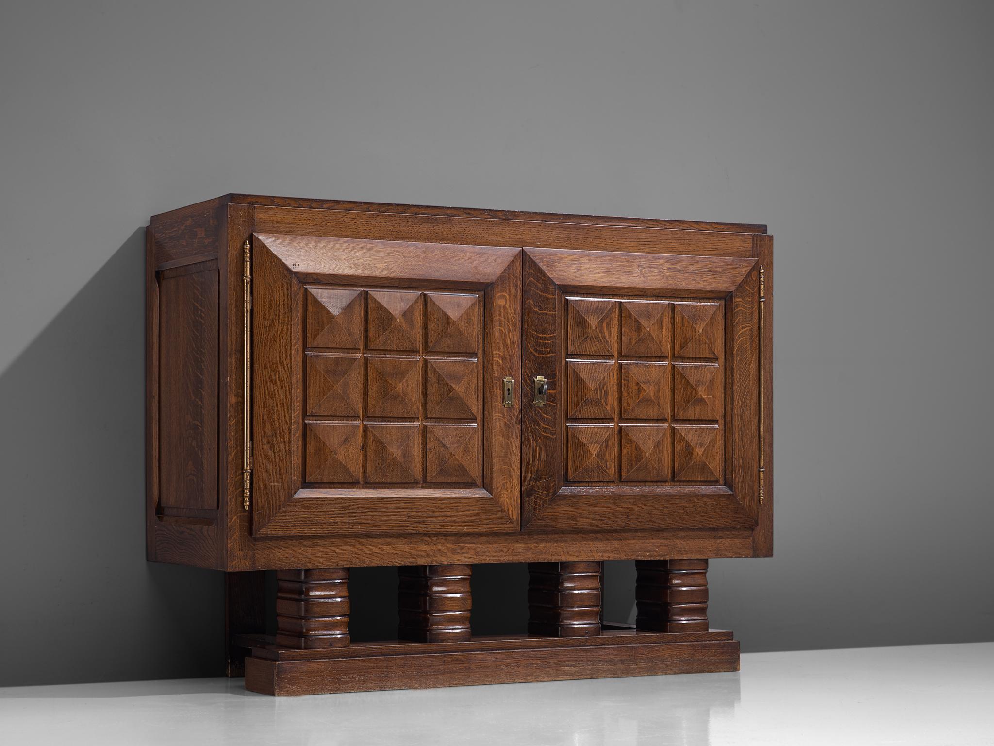 Art Deco cabinet, stained oak, brass, France, 1930s

Sturdy and beautifully detailed cabinet in oak with graphical panelled doors. This sideboard is equipped with several shelves which provide plenty of storage space. The door panels and base show