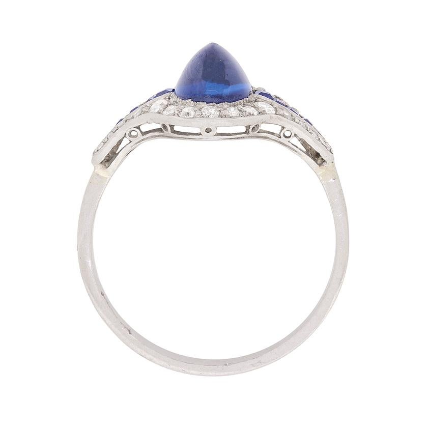 This unusual and intriguing ring features a 2.80 carat cabochon cut sapphire in the centre, which just shines. It is a fantastic blue, and is highlighted wonderfully by a stream of sapphires on either side which total 0.15 carat. They are french cut