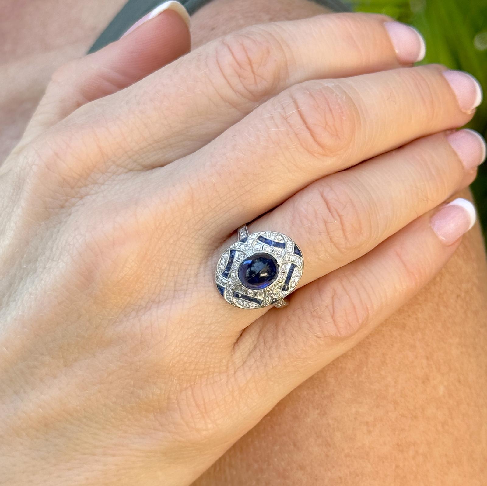 This exquisite cocktail ring epitomizes the elegance of the Art Deco era with its capitavting design. The ring features a stunning approximate 2.00 carat cabochon sapphire as its centerpiece. Encircling the sapphire are 50 single cut sparling