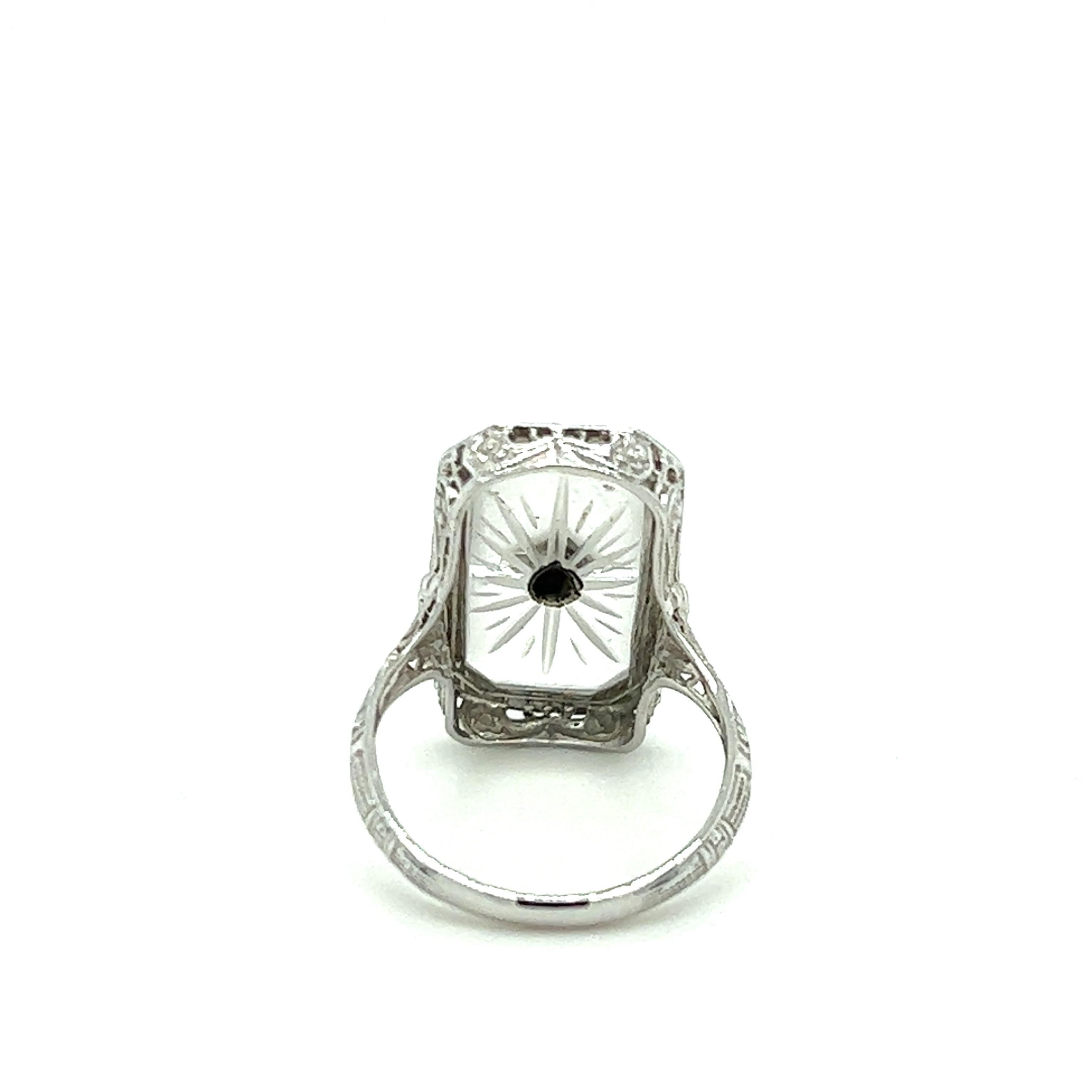 One 1920s Art Deco 14 karat white gold (stamped 14k) filigree camphor glass ring set with one round diamond, approximately 0.03 carat with J/K color and SI1 clarity.  The top of the ring measures 20.80x11.80mm and weighs 3.0 grams total weight.  The