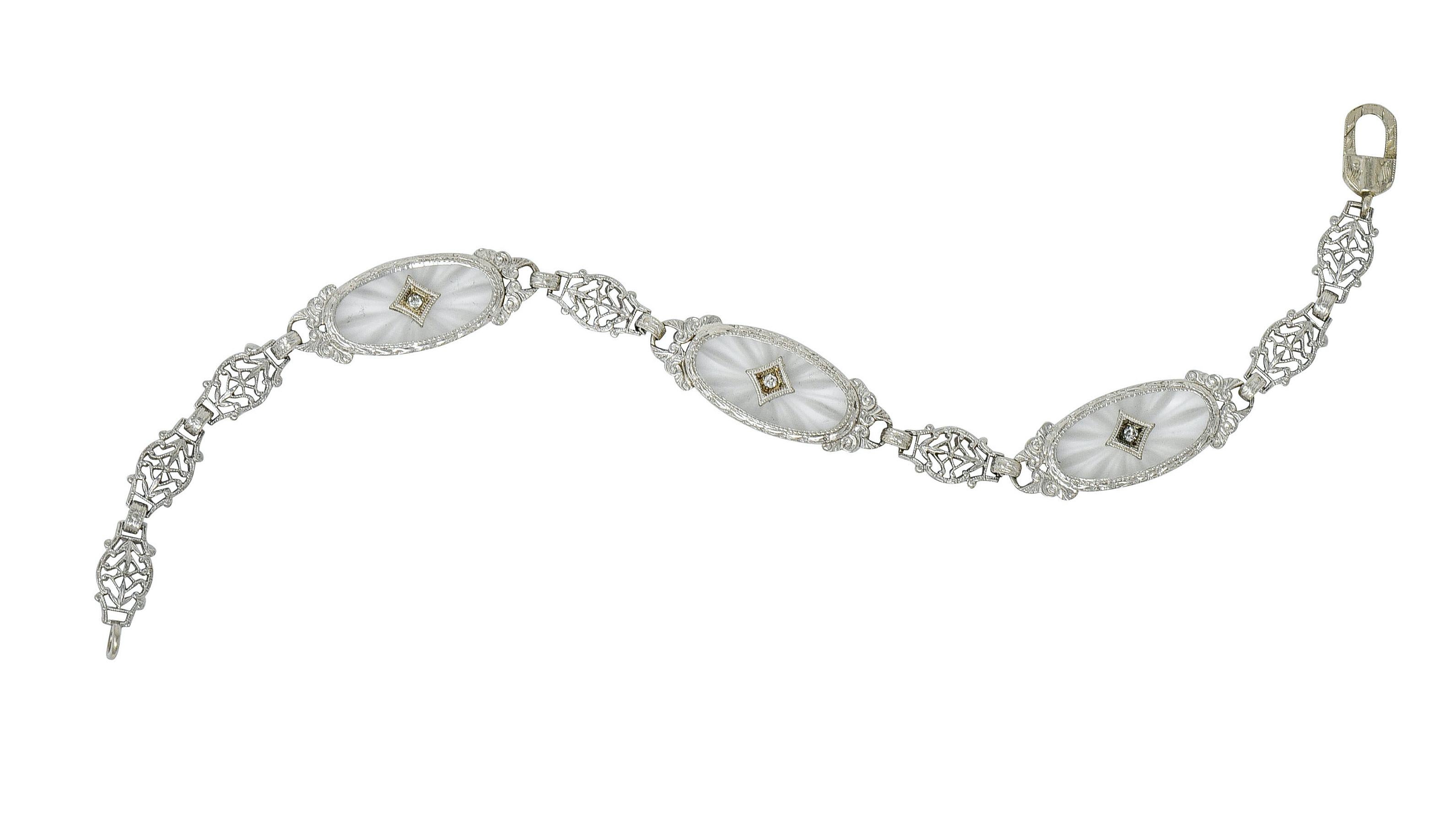 Link style bracelet features three oval tablets of camphor glass measuring approximately 7.5 x 16.5 mm; frosted with a radiating pattern

Each oval centers a milgrain navette form set with a single cut diamond, weighing in total approximately 0.08