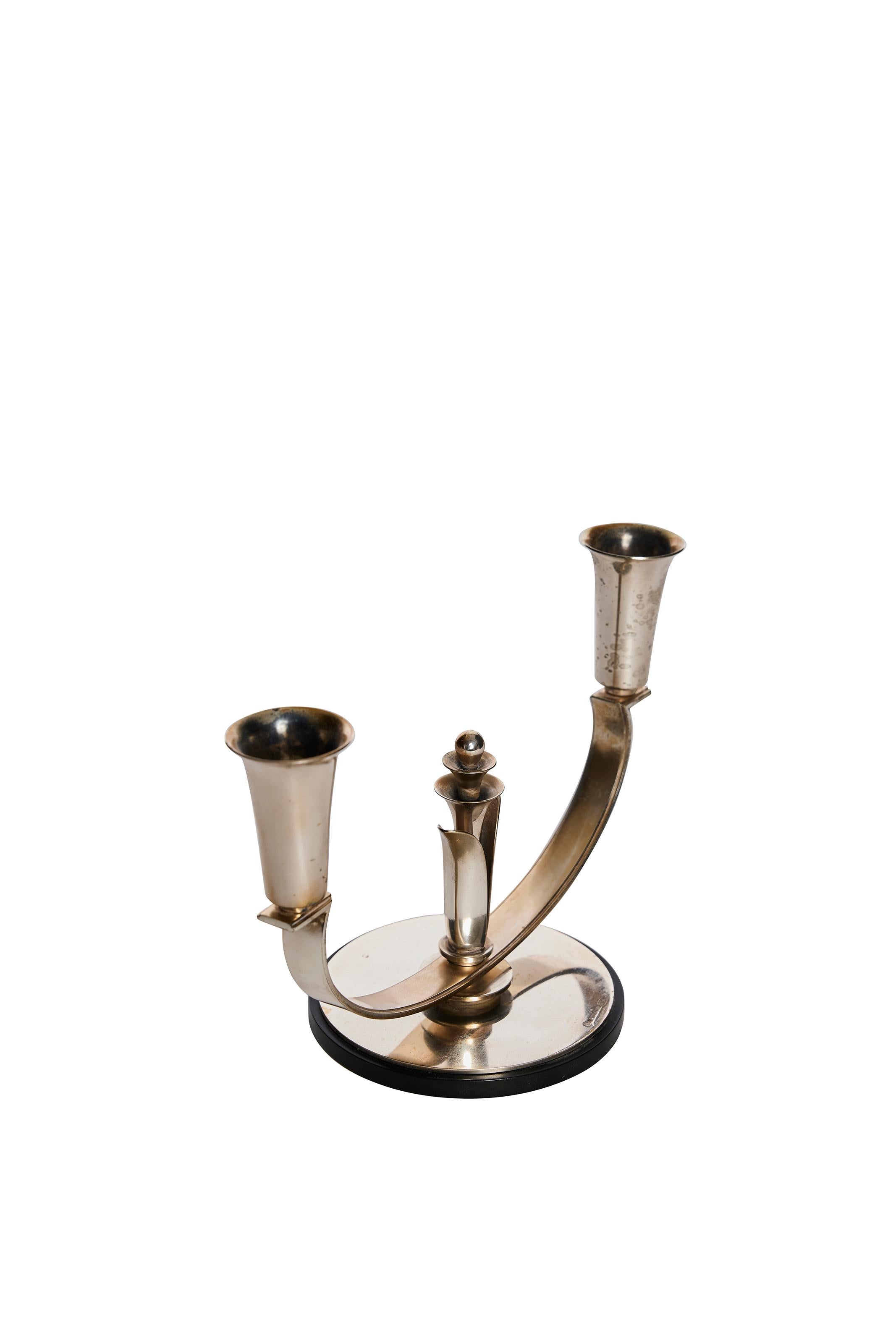 Un elegante candelabro a due bracci realizzato in alpacca da Alta of Denmark, databile tra la fine degli anni '20 e l'inizio degli anni '30. Questo raffinato pezzo riflette il fascino dell'Art Déco per la simmetria, la forma e gli ornamenti